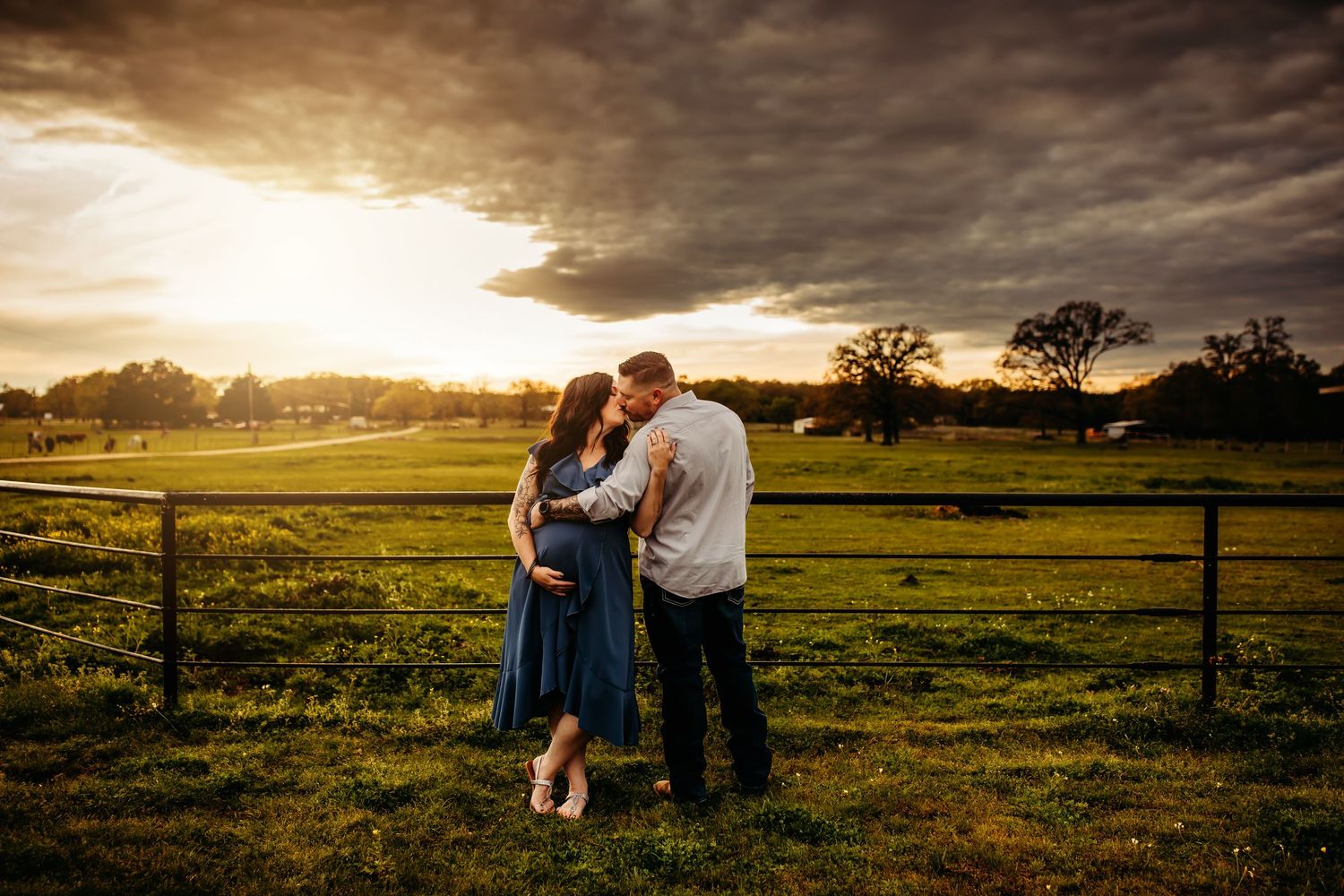 A family enjoys a sunset moment together in a golden field with dramatic storm clouds overhead.