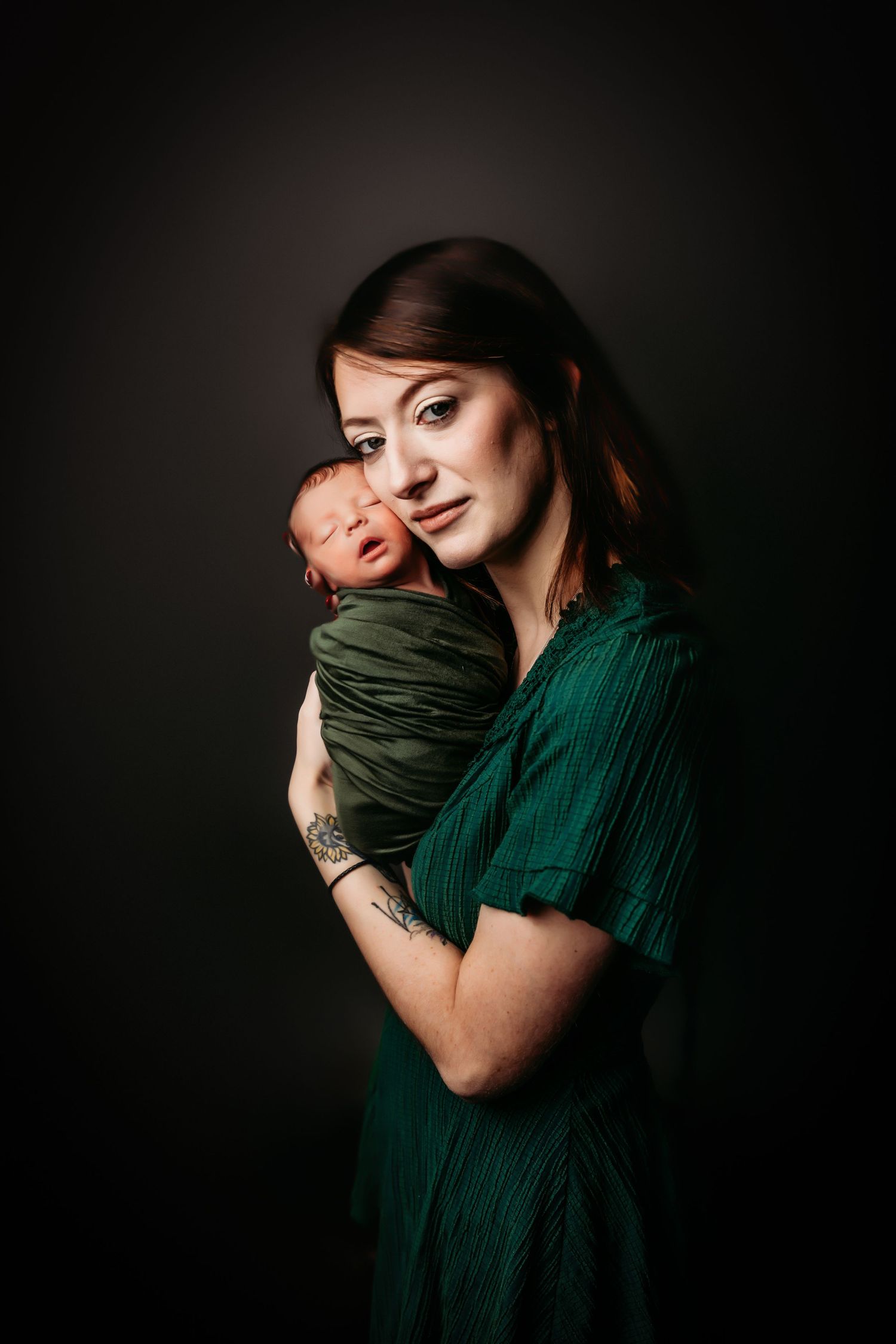 Dramatic studio portrait in dark setting with emerald green clothing.