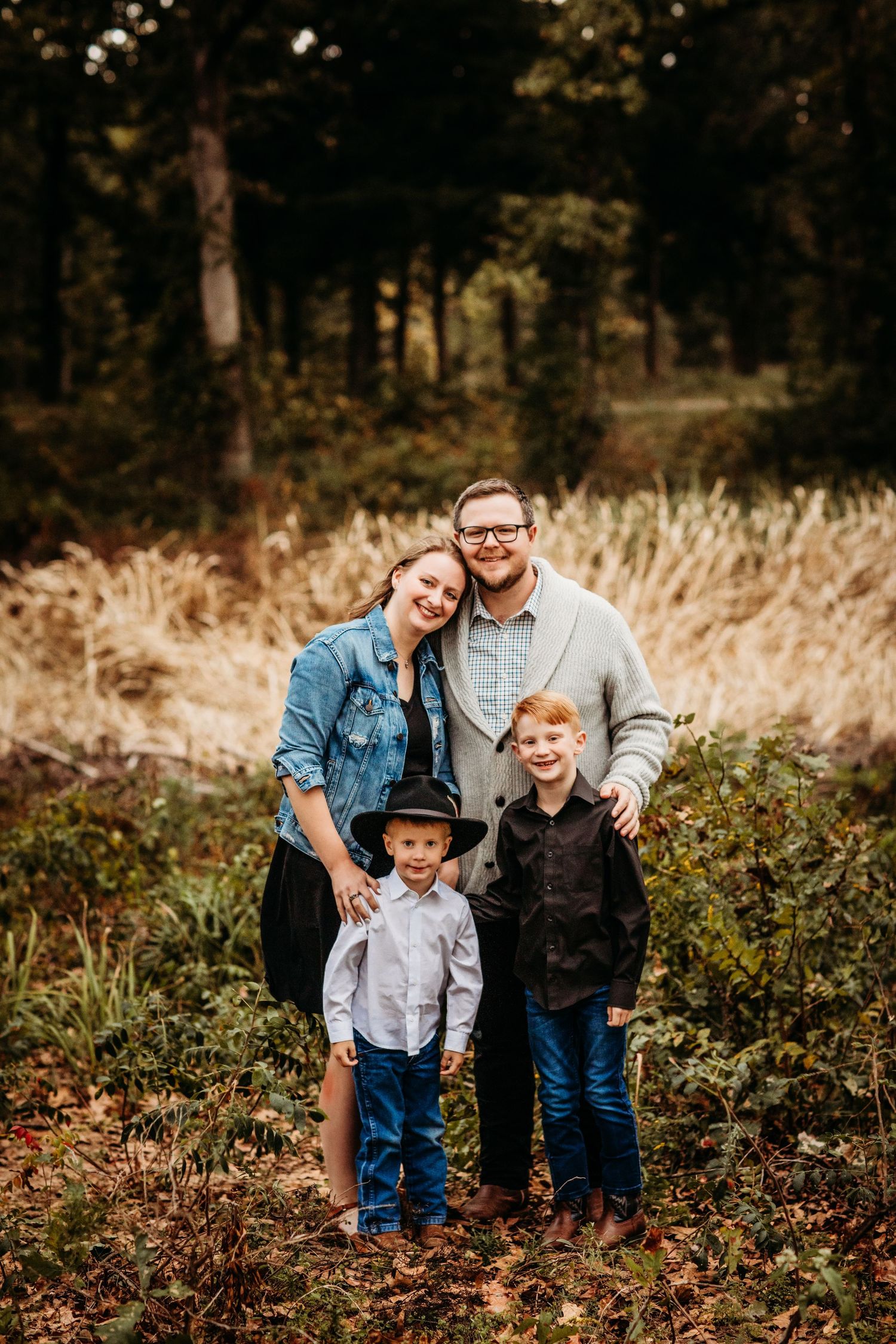 Autumn family portrait in a wooded setting with fall foliage.