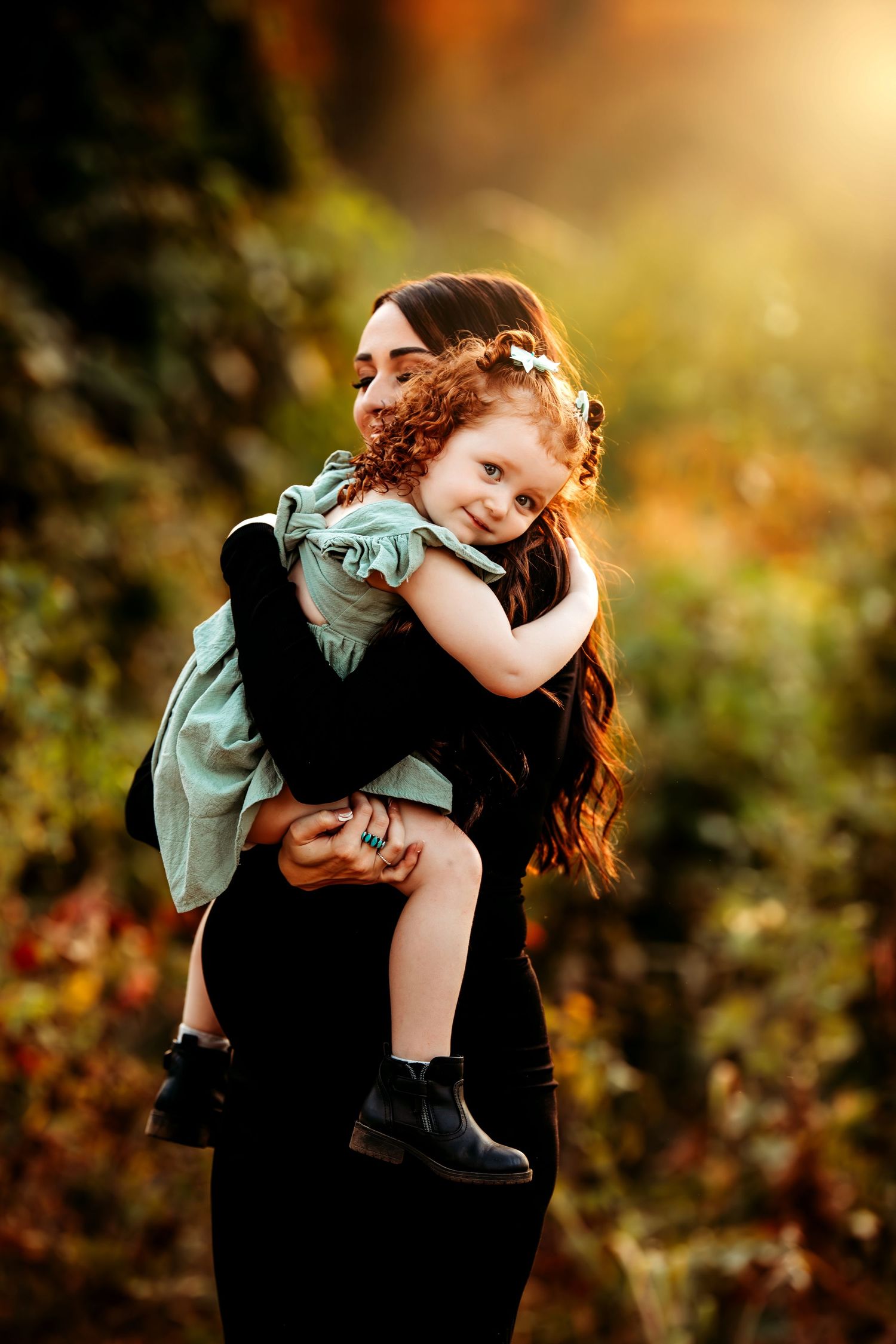 Tender moment captured in golden sunlight with gentle embrace and natural backdrop.