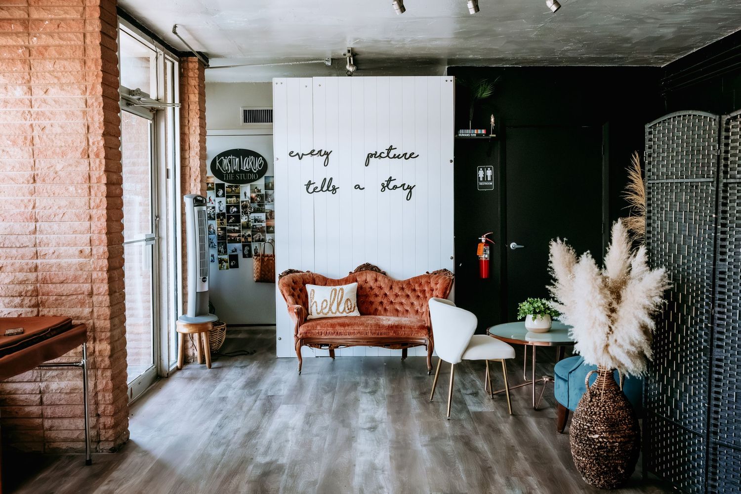Eclectic photography studio with vintage orange velvet sofa, white chair, and every picture tells a story wall quote.