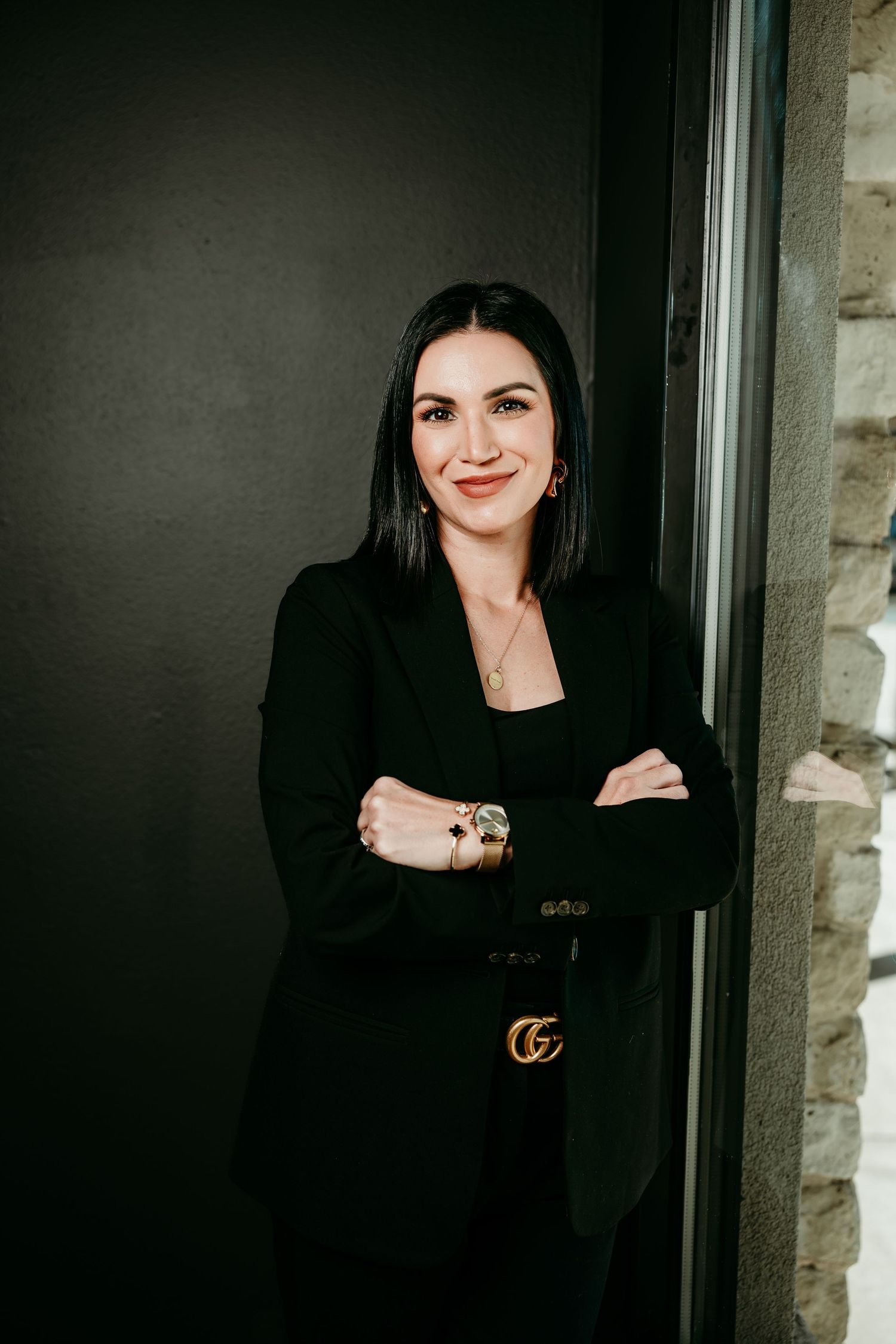 A person in a black outfit with a Gucci belt poses against a dark background in a photo series.