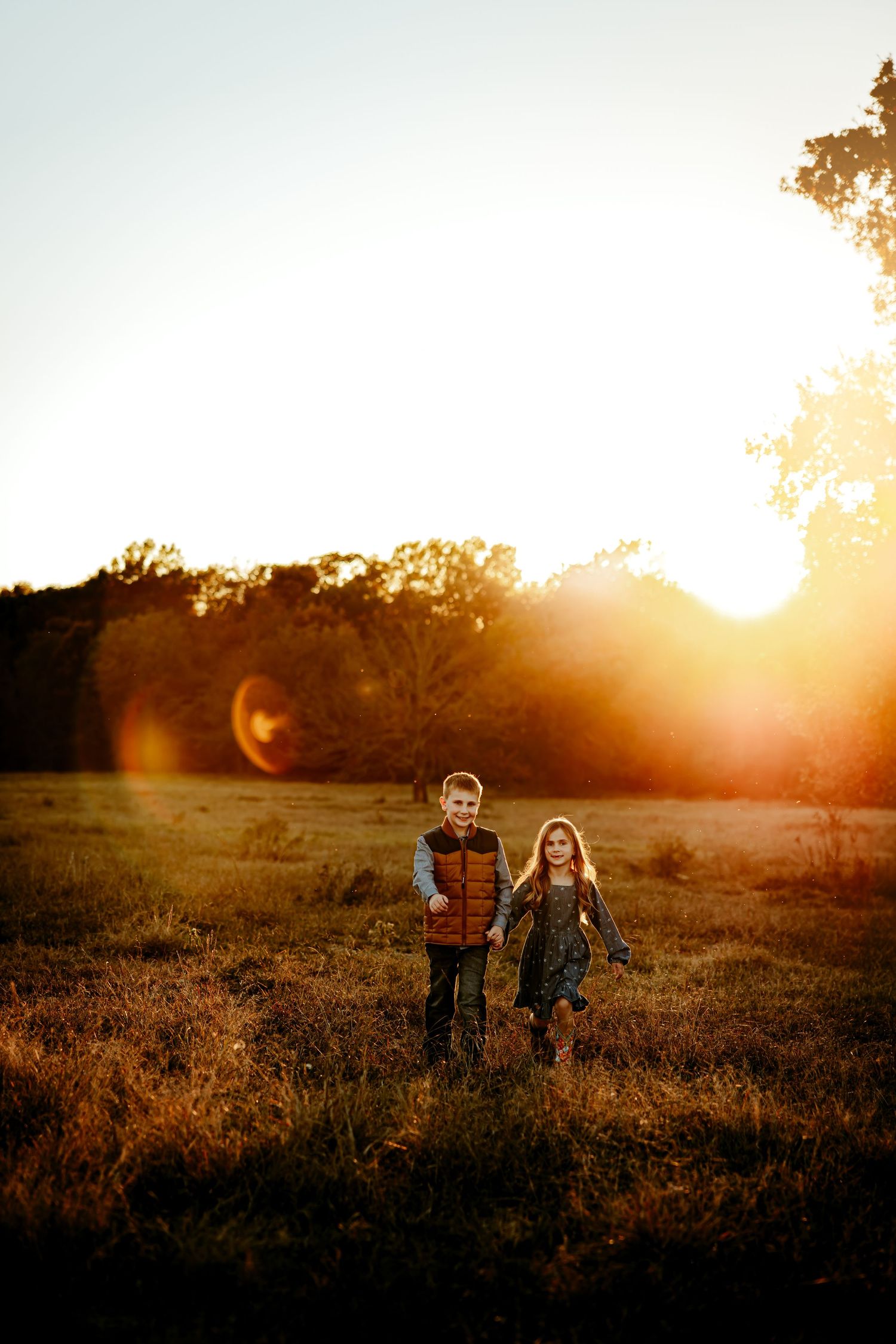 Silhouettes of people playing in a golden field at sunset with warm glowing light in the background.