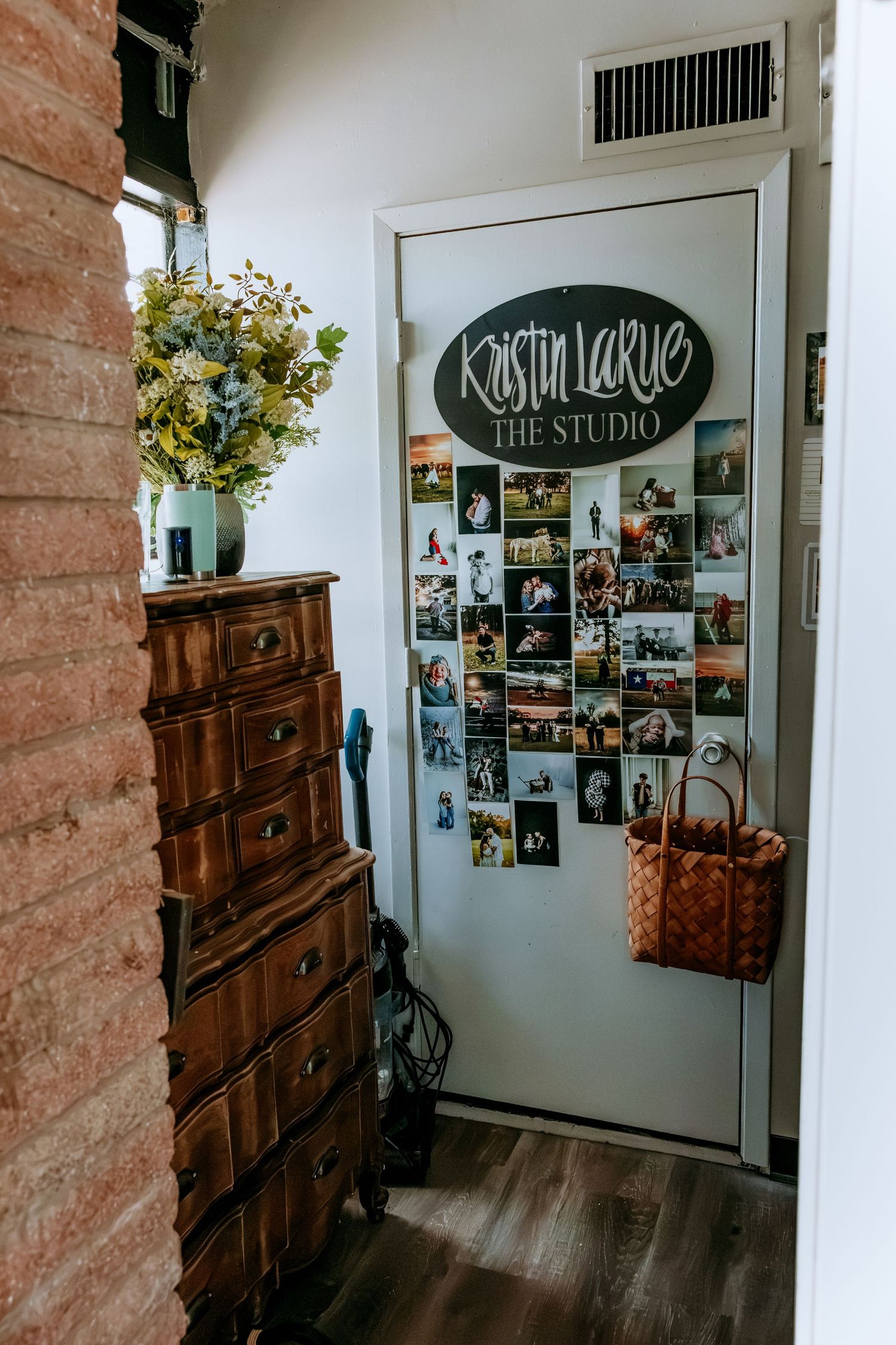 Kristin LaRue photography studio entrance with vintage dresser, floral arrangement, and photo collage on white door.