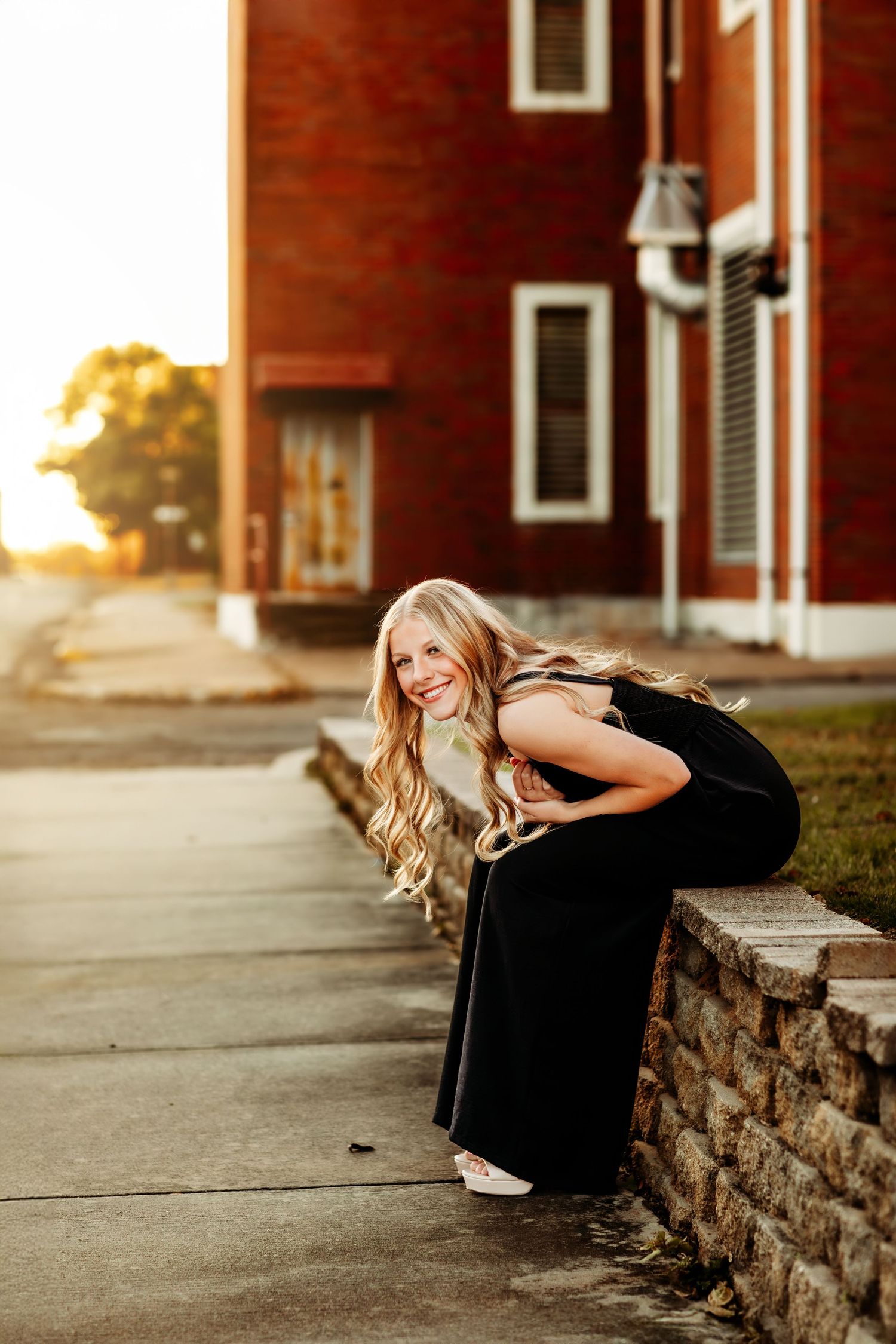 Athletic figure performs stretches on stone wall during golden hour.