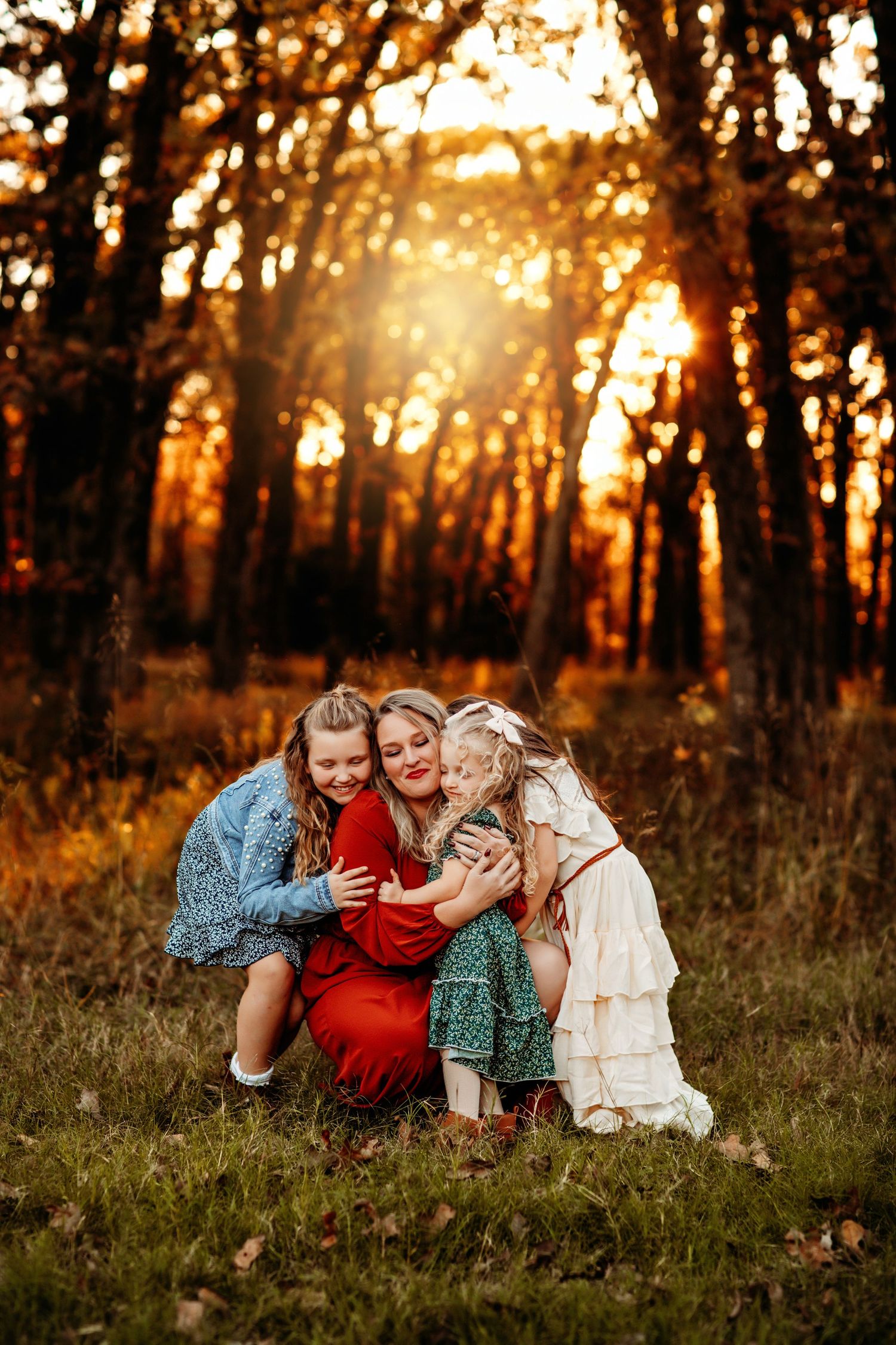 A joyful family moment captured in a golden forest at sunset with warm autumn colors and glowing sunlight through trees.
