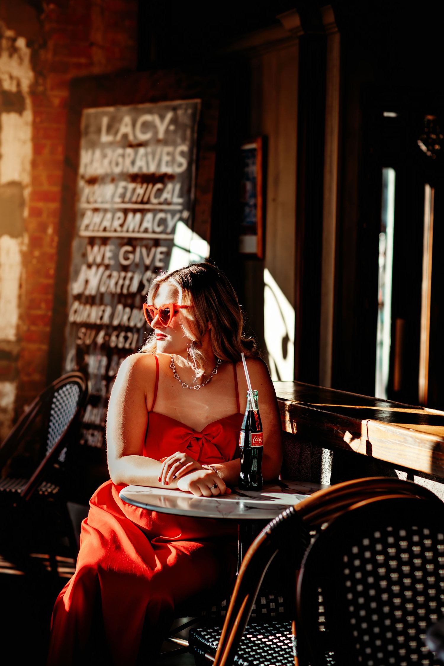 Artistic cafe scene with red dress detail and vintage pharmacy signage.