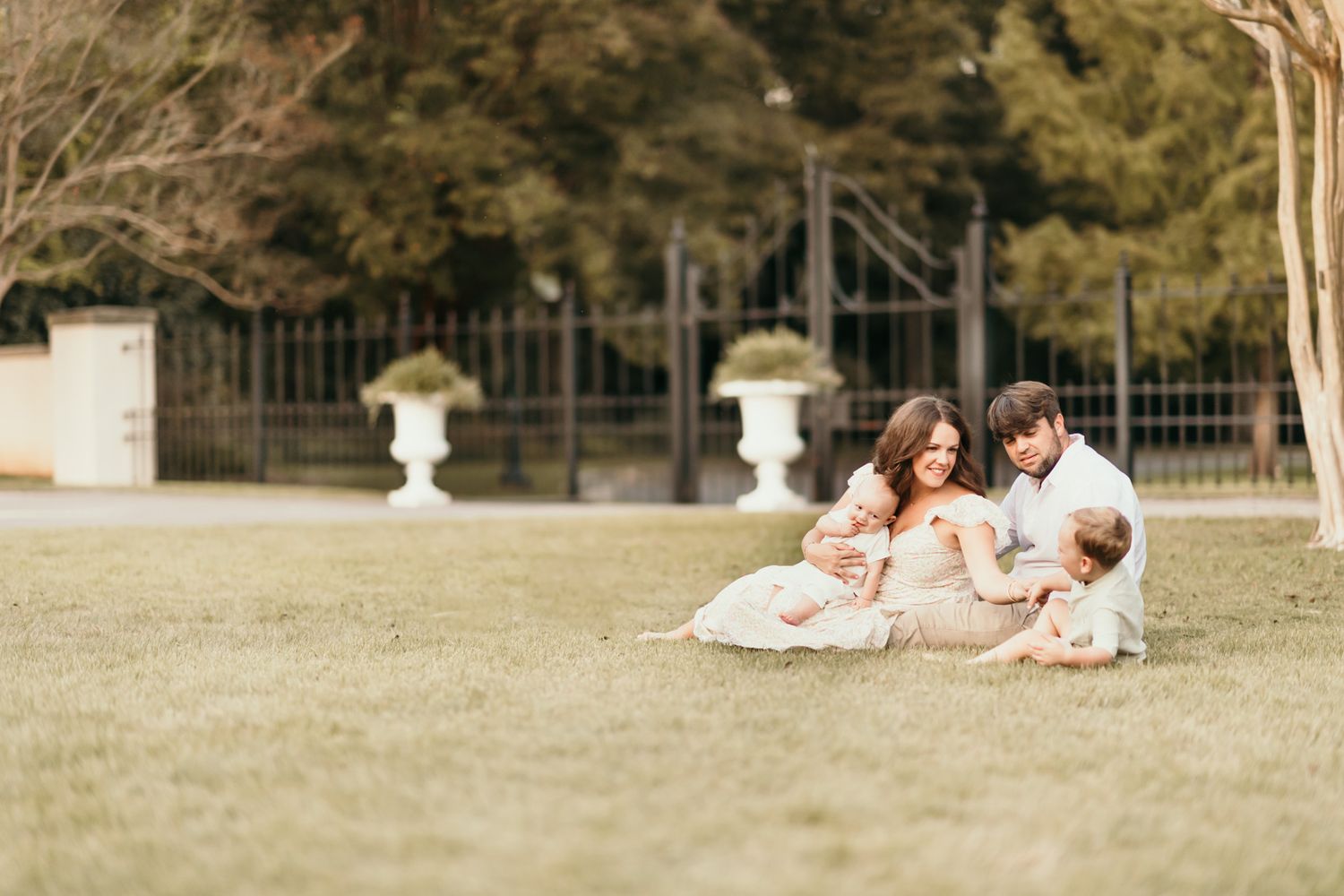 Family members lounging together on a sunny lawn with trees in the background.