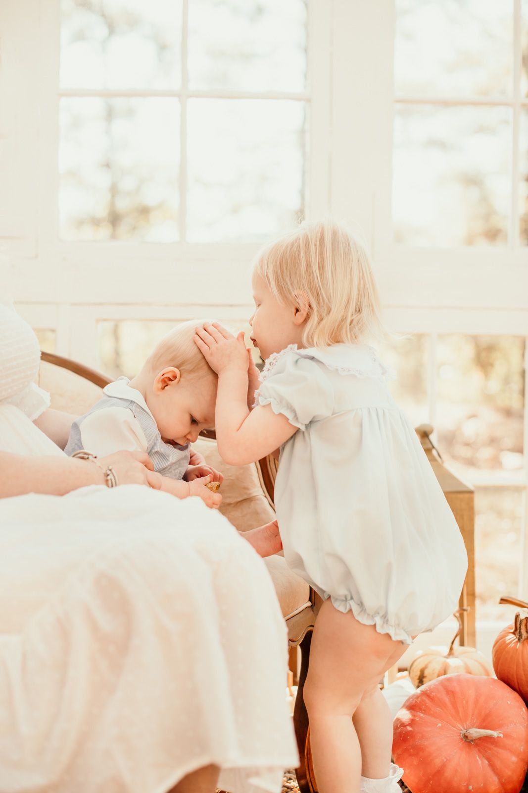 Sweet candid moment captured in bright sunlit room with autumn decor.