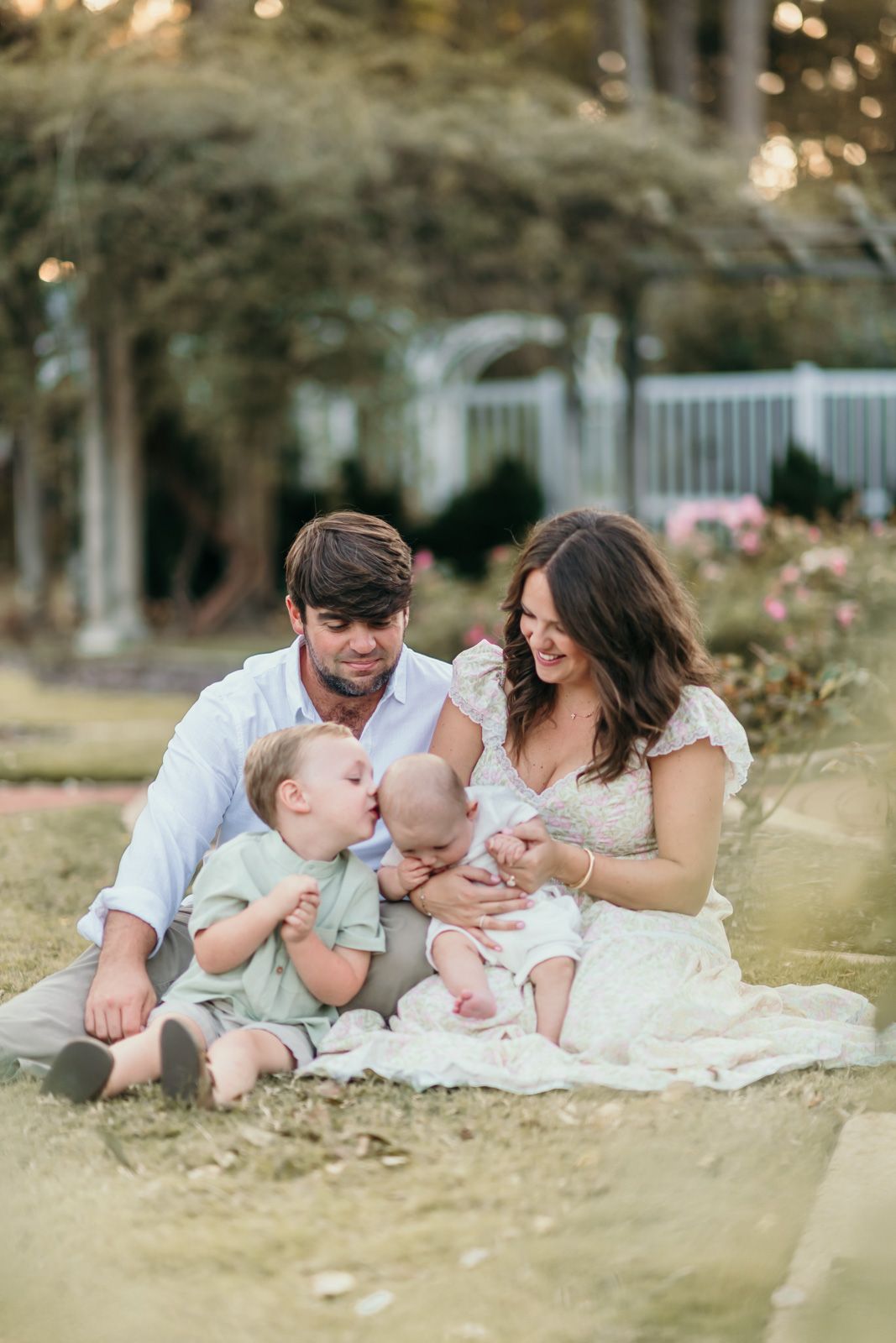 Family lies together on grass during sunset for casual outdoor portraits.
