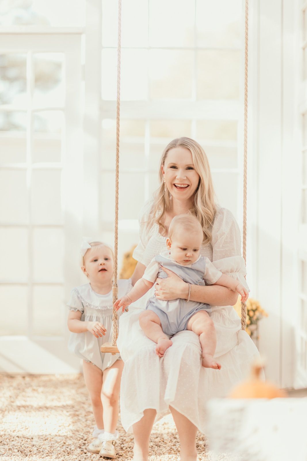 A playful indoor photoshoot with a toddler on a swing in a bright sunlit room.