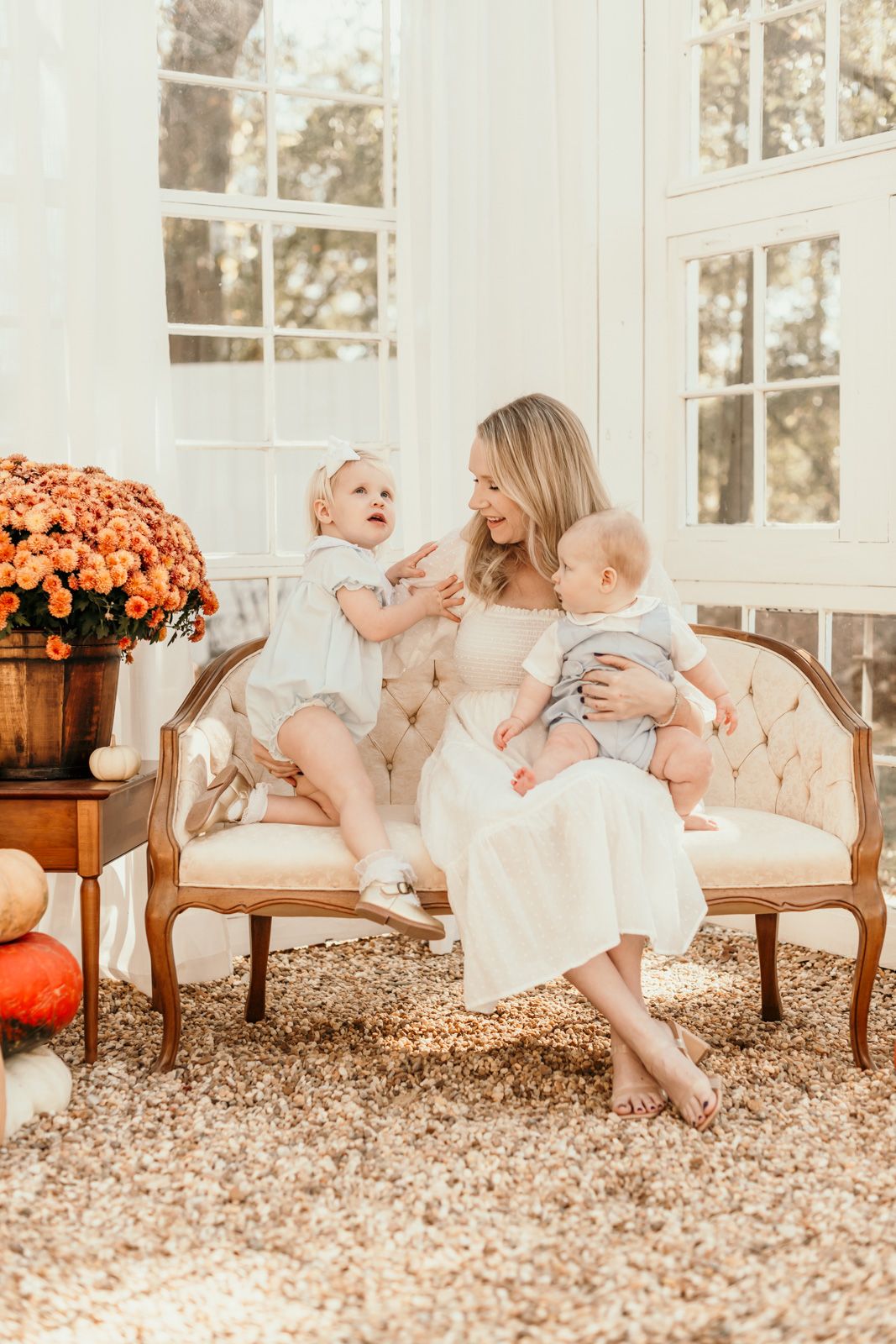Candid moments captured on a vintage sofa with orange mums adding autumn warmth to the scene.