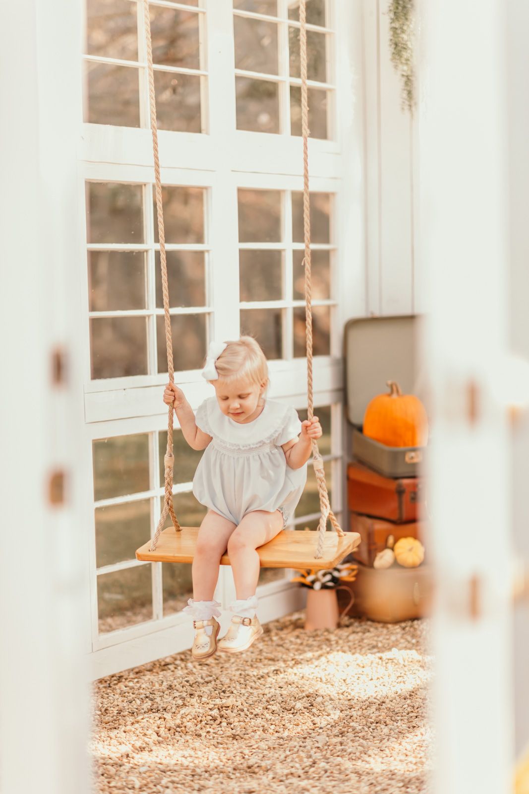 Indoor fall setting with white French doors, pumpkins, and a wooden swing.