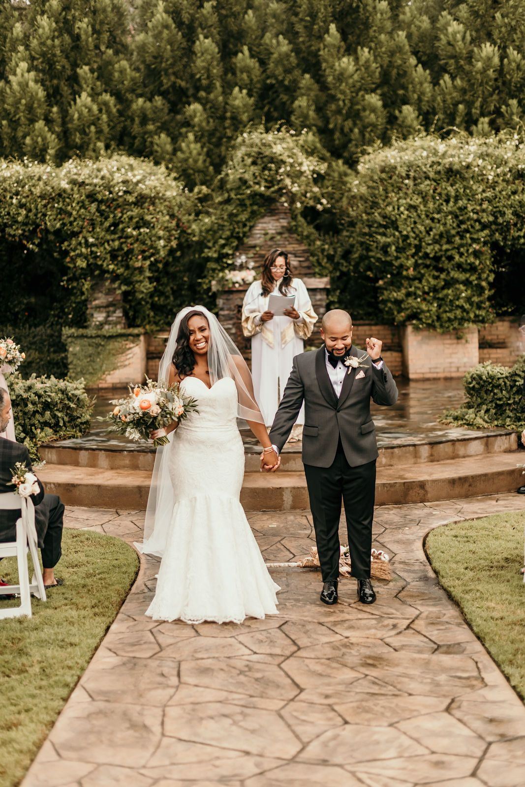 A wedding ceremony sequence captured outdoors on a stone patio surrounded by lush greenery and trees.