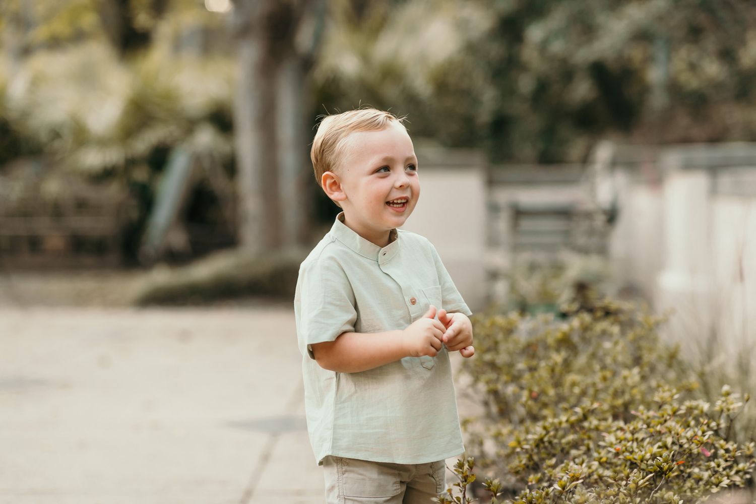 A young child plays and smiles in a garden setting with natural lighting.