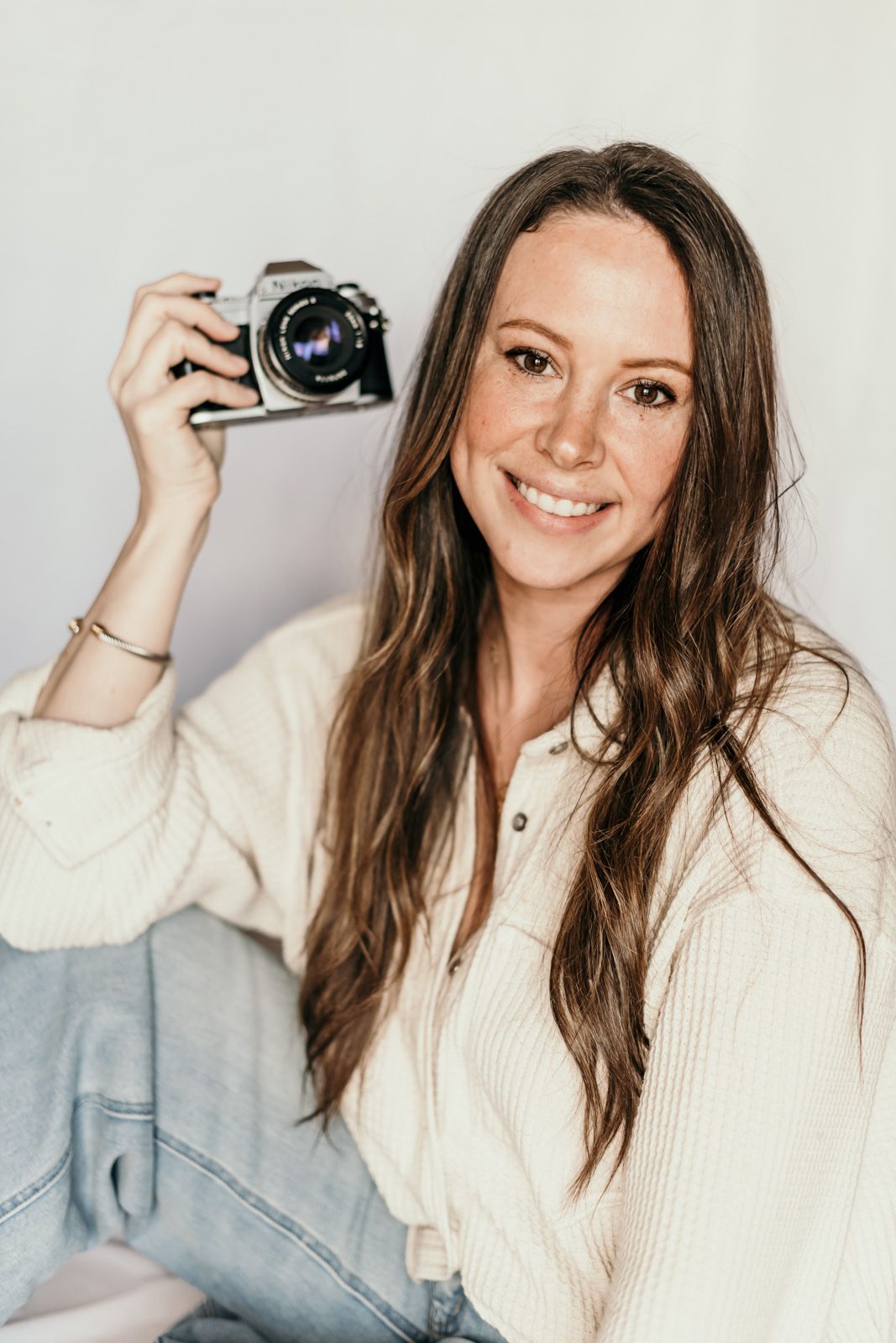 Professional headshots in cream sweater showing various poses with camera against white backdrop.