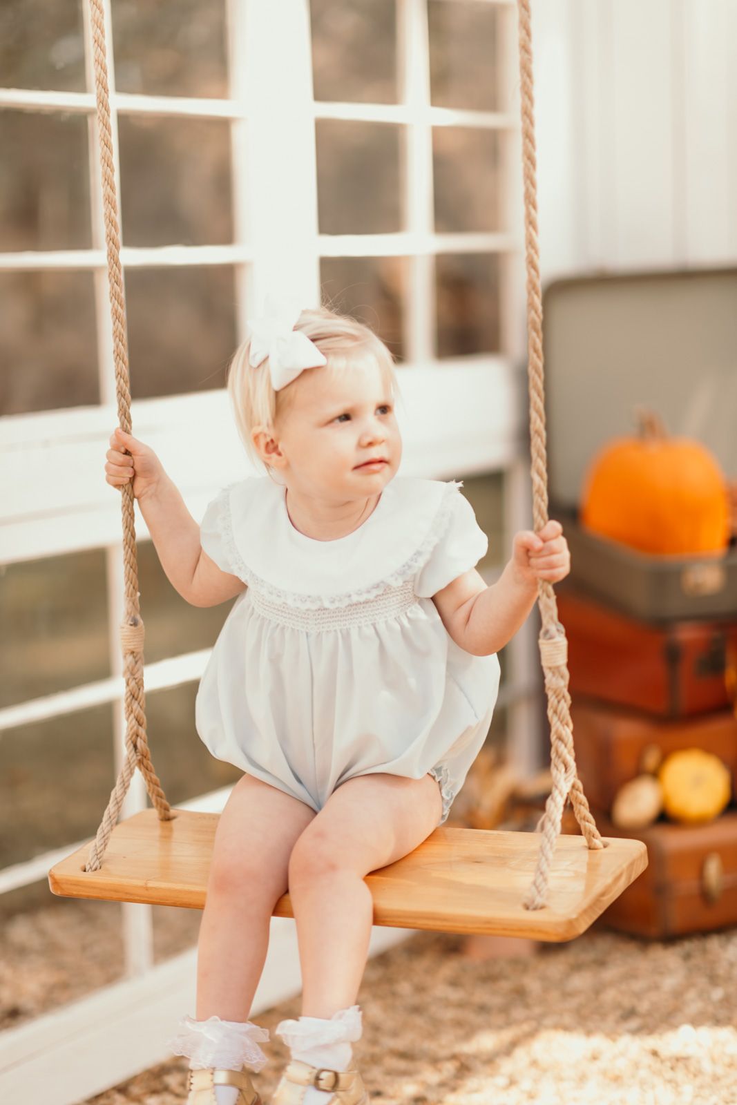 Rustic wooden swing against white French doors with fall decorations.