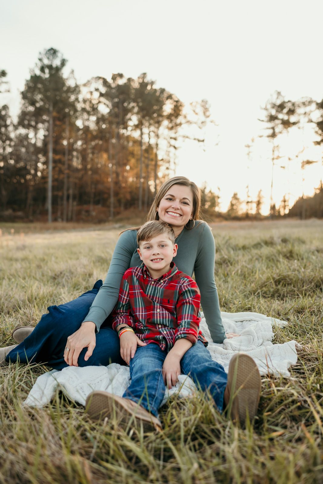 A heartwarming outdoor family photo session in a grassy field at sunset with warm golden lighting.