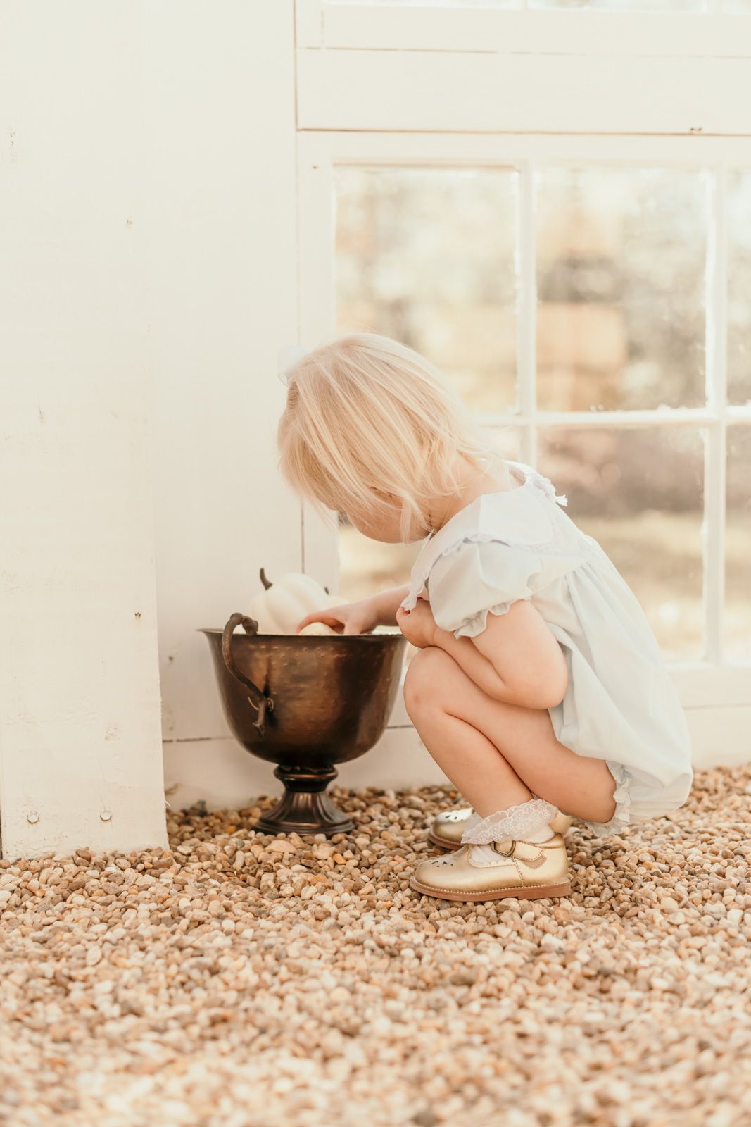 Vintage copper bowl sits on floor near white French doors in warm lighting.