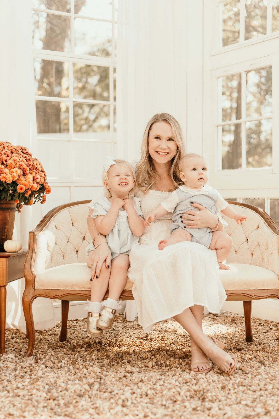 Sweet family interactions on a tufted beige sofa with orange flowers in the background.