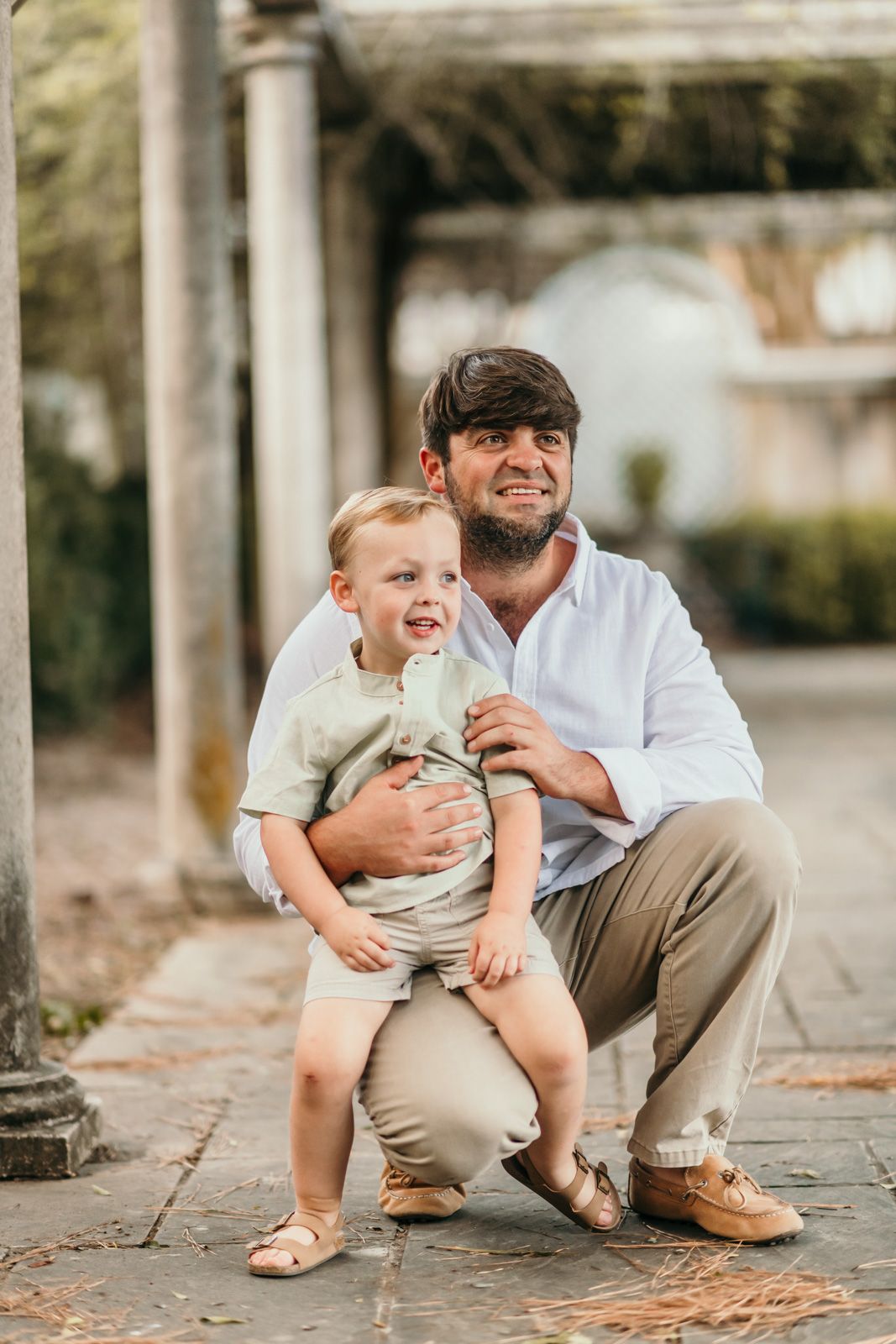 Parent and child share a playful moment under a columned walkway.