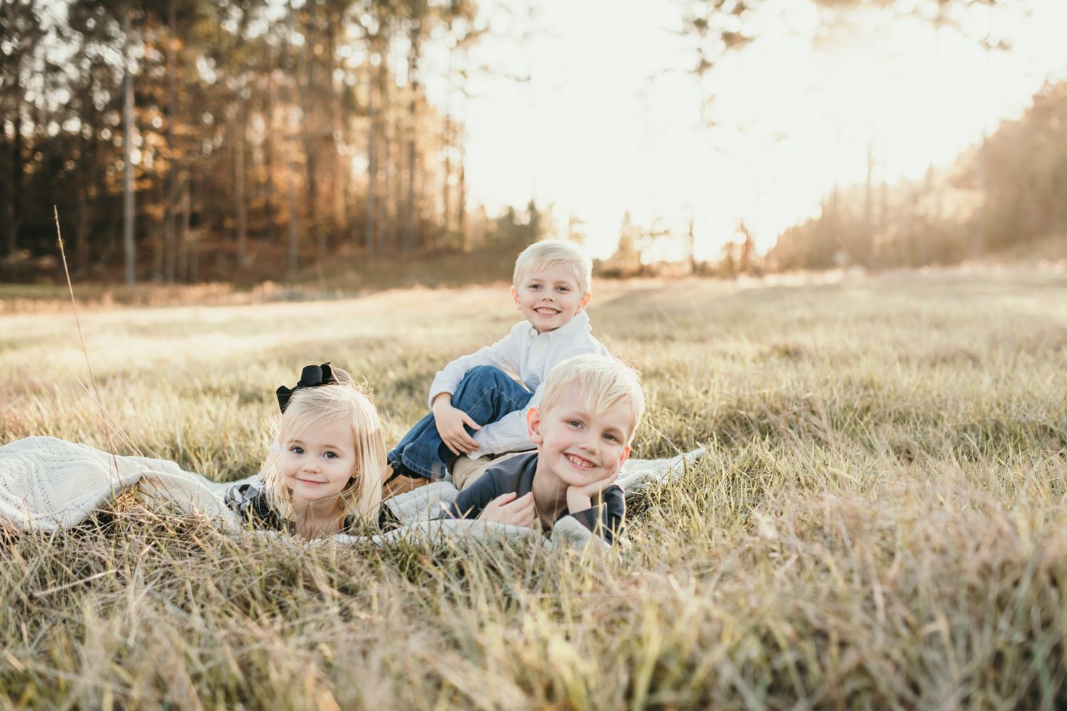 Children sitting together in a sunlit golden field during sunset creating a warm autumn atmosphere.