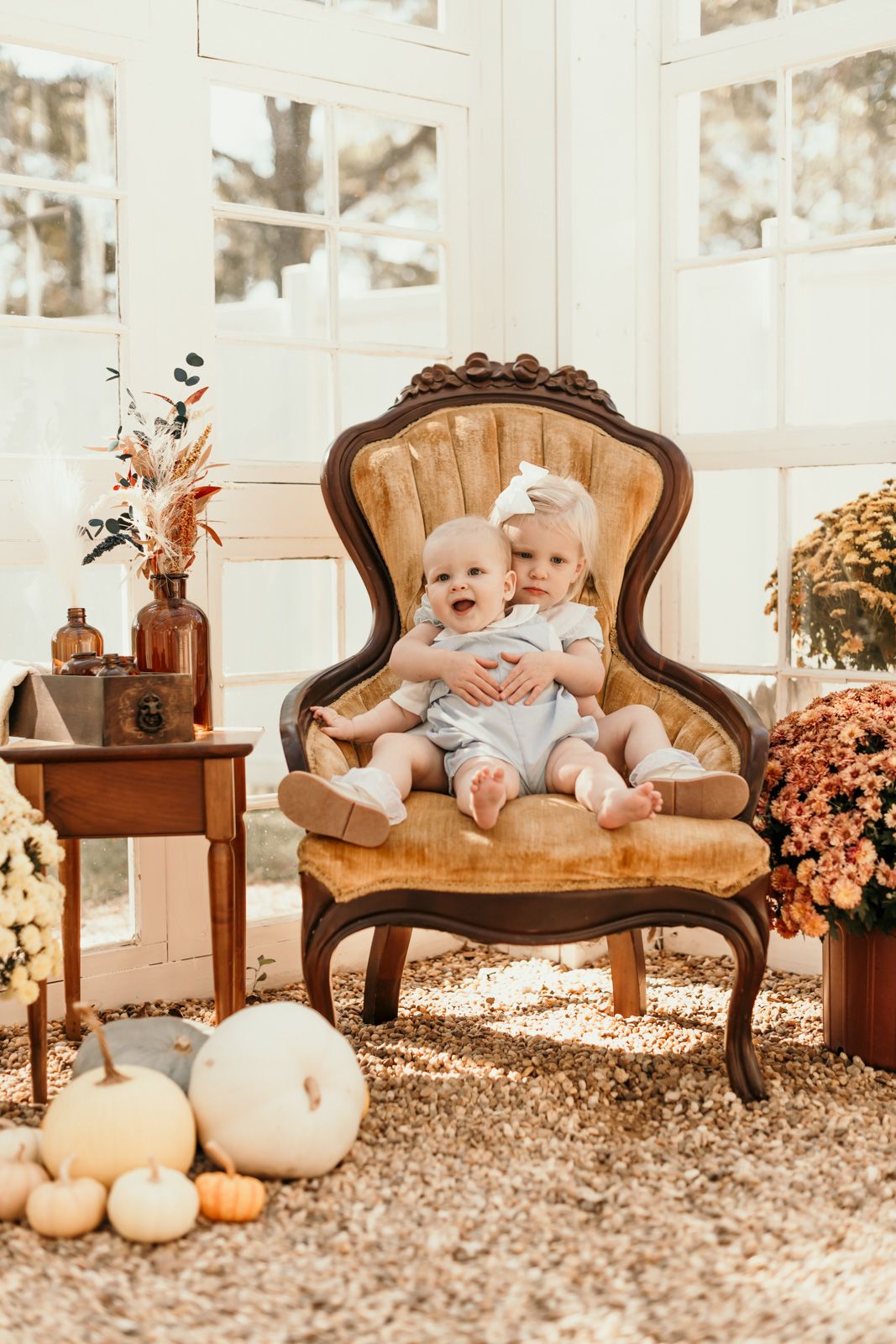 Vintage brown armchair decorated with pumpkins and dried flowers in a bright sunlit room with fall decor.
