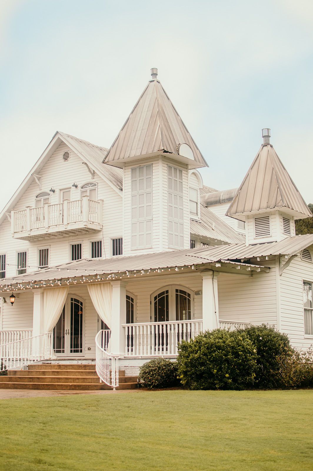 Row of charming white Victorian-style cottages with pointed roofs and porches on a grassy lawn.