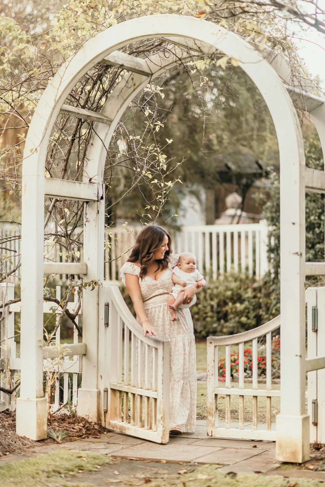 A tender moment under a white garden arbor with flowing dress and soft natural lighting.
