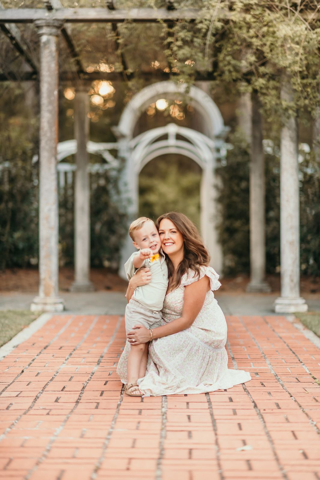 A sweet moment shared between a parent and child on a brick patio surrounded by white columns and arches.