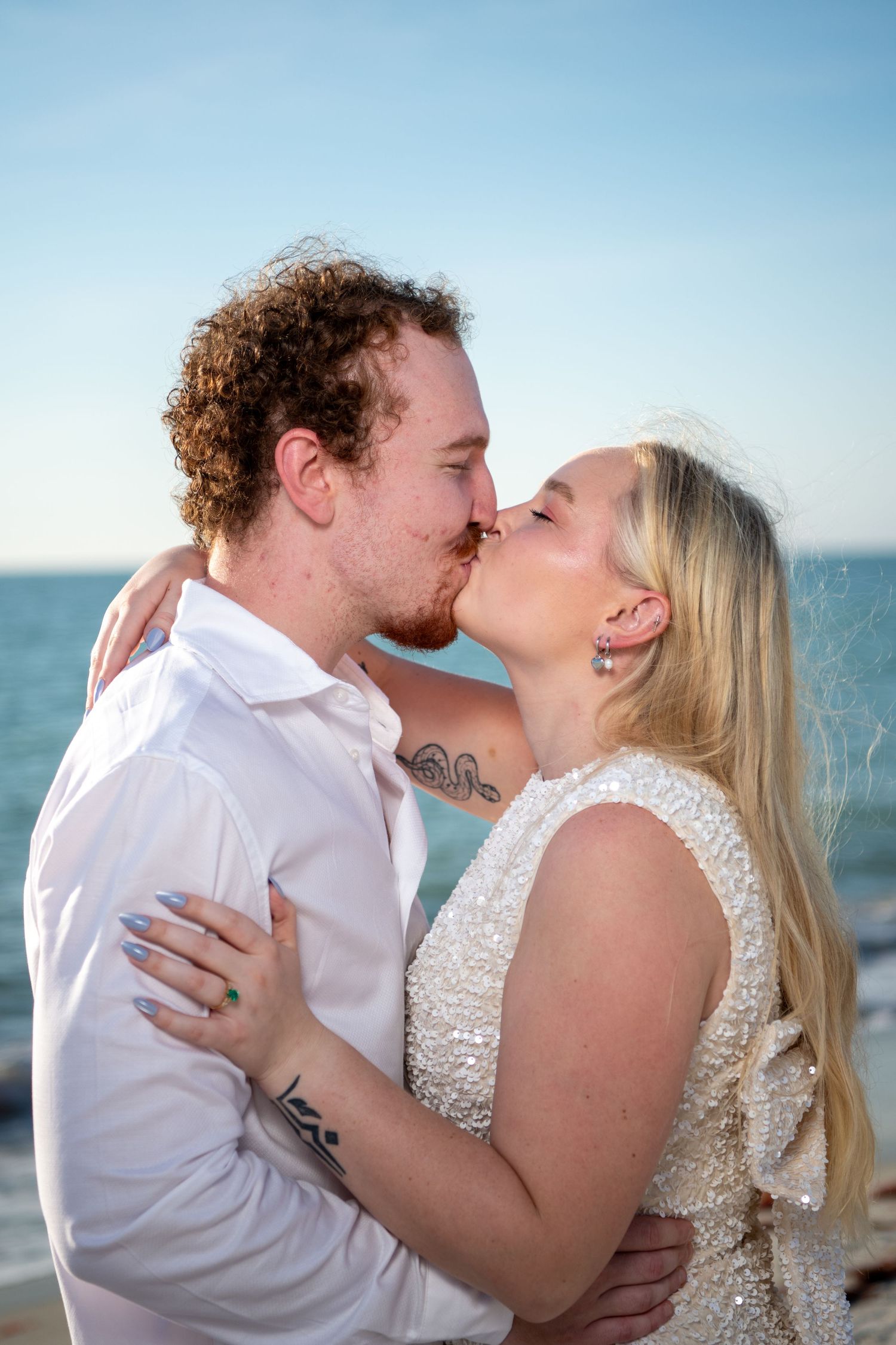 Intimate beach portraits showing tender moments between a couple in white attire. Engagement photoshoot. Couples photos.