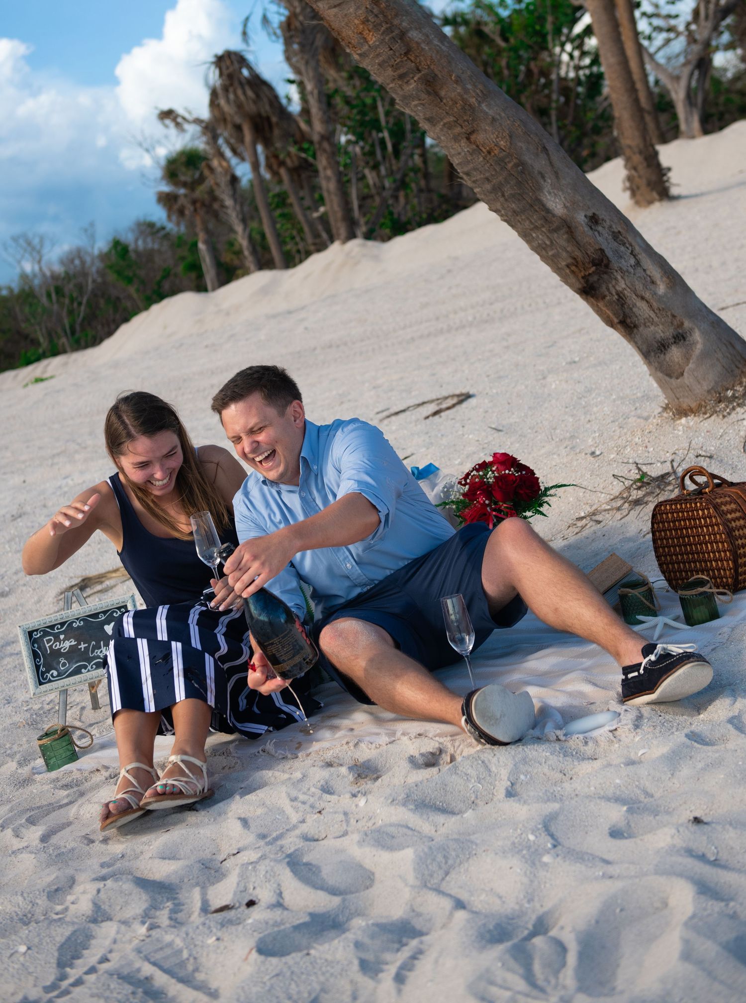 Playful couple lying in white sand on a tropical beach.