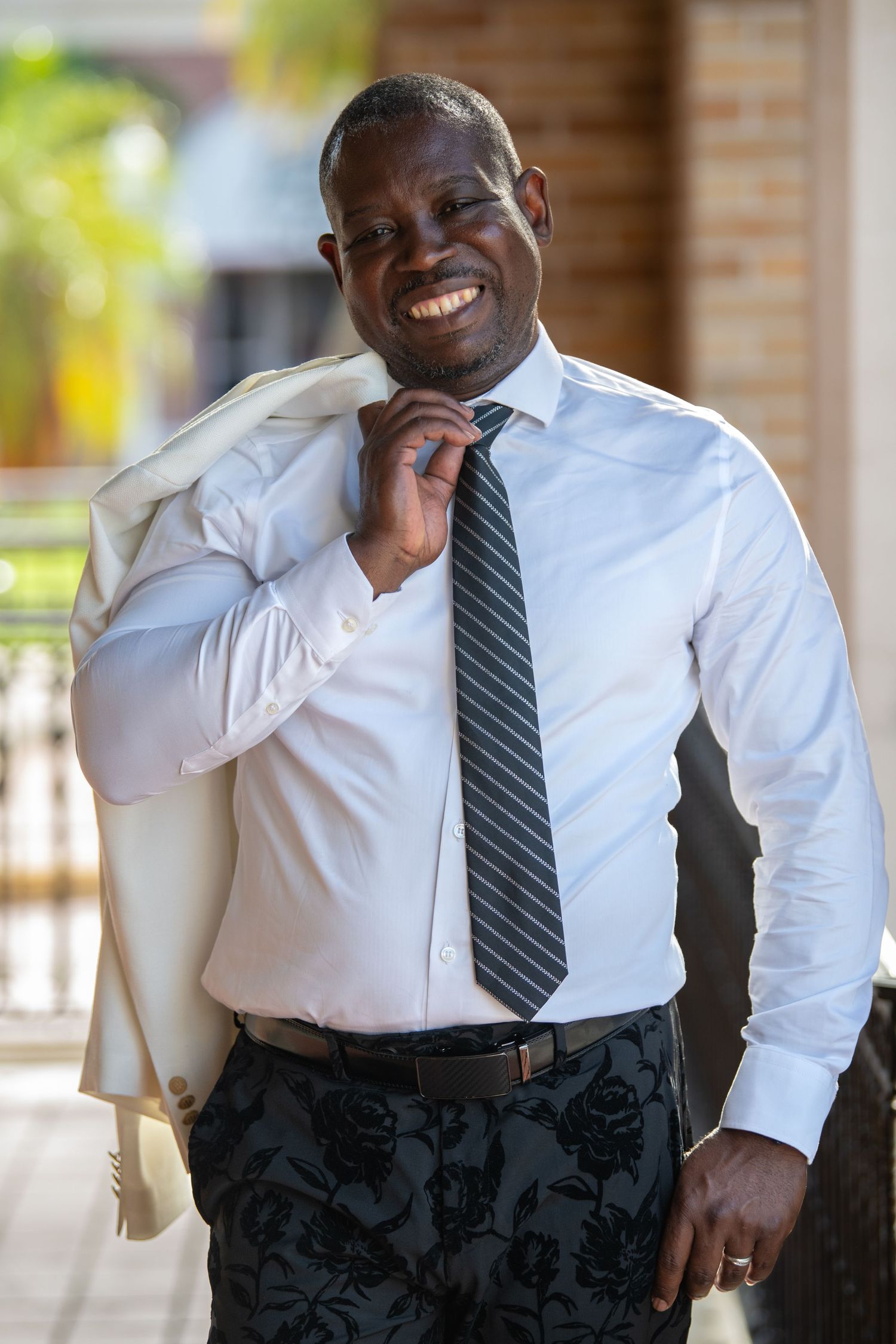 Person in business attire with white shirt and tie leaning thoughtfully against a wall.