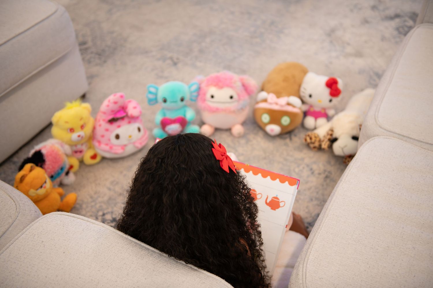 Collection of colorful plush toys and stuffed animals arranged on light colored surface.