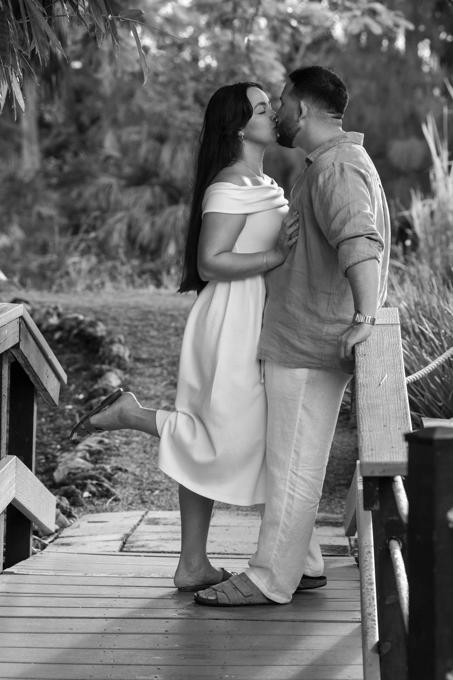 A black and white photo captures intimate moments between a couple on a wooden walkway.