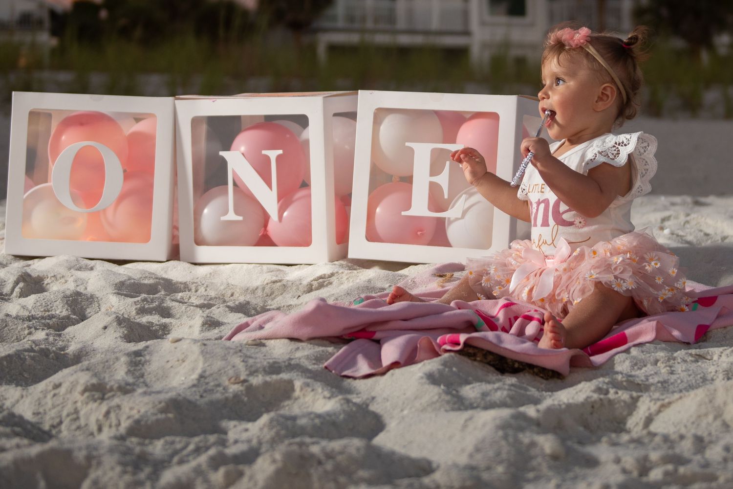 Decorative letter blocks arranged on white sand during golden hour.