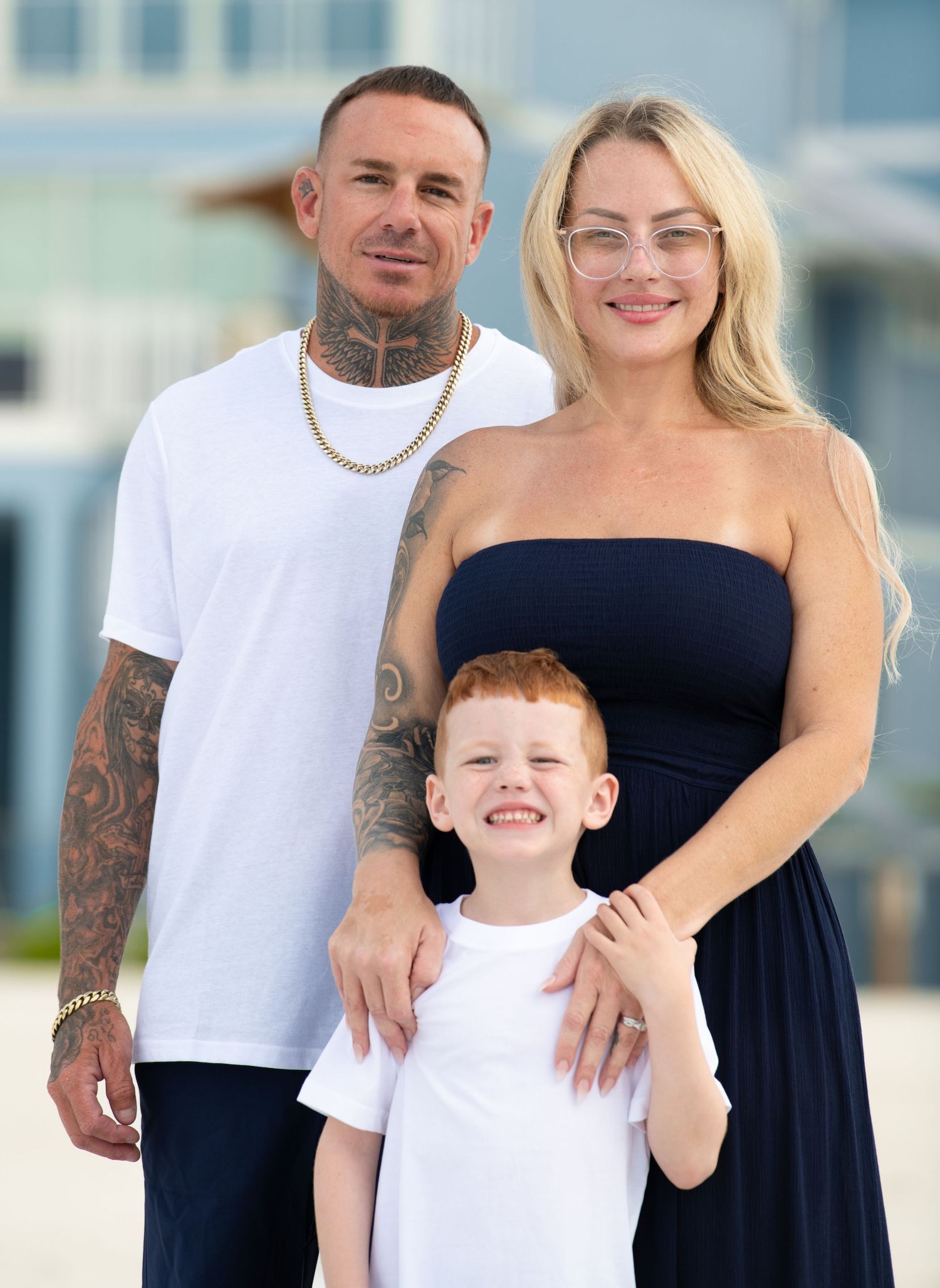 Candid family moments captured on sunny beach with coastal architecture.