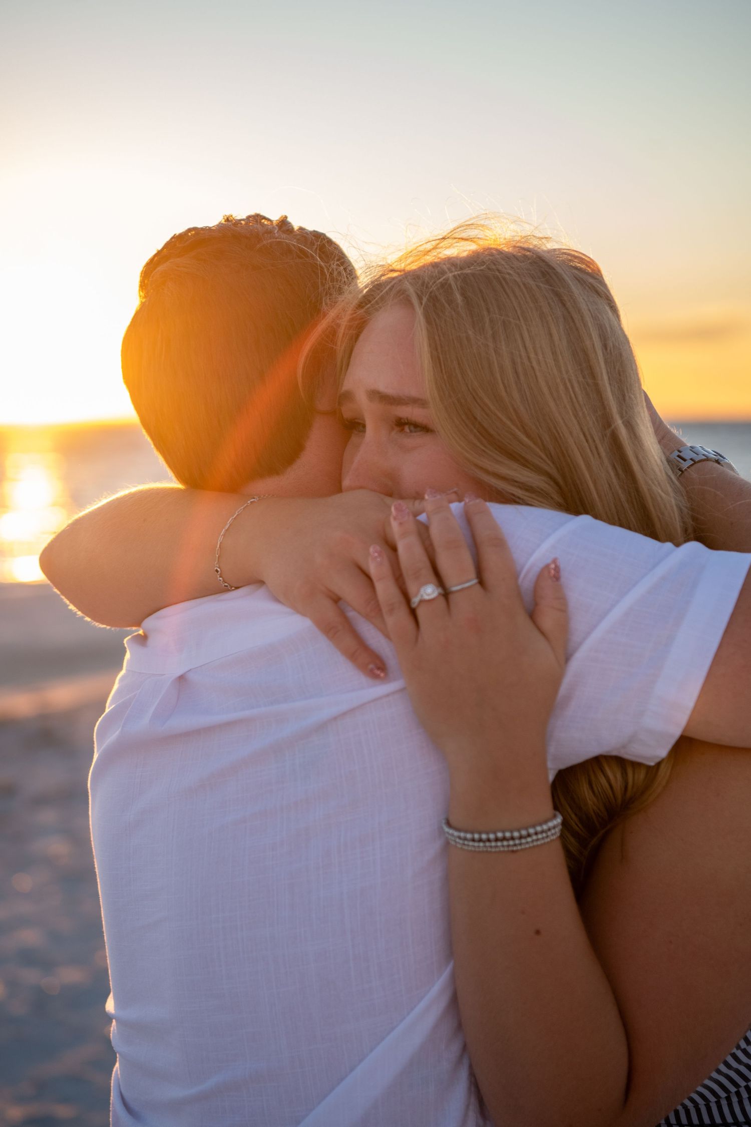 Romantic beach sunset scene with couple embracing on sandy shore.