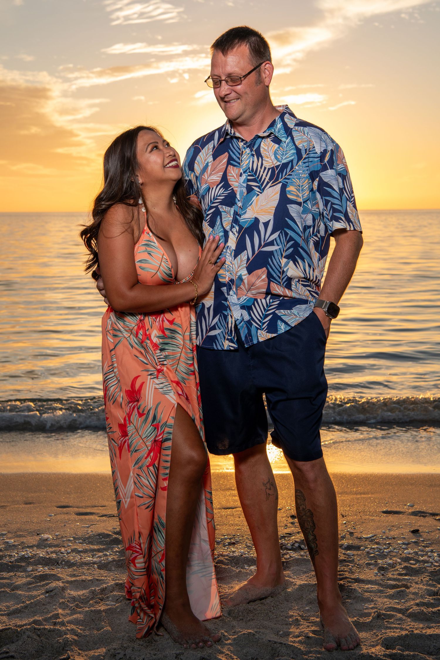 Couple in matching floral outfits sharing a romantic moment on beach at sunset. Beach photoshoot. Family photoshoot,