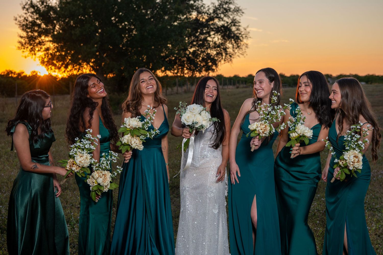 Bridal party in elegant emerald green dresses poses together at golden hour. Wedding photography.