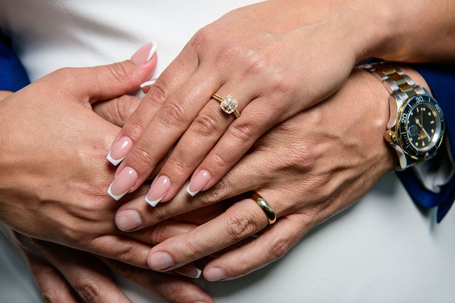 Wedding portraits of hands with wedding rings resting against formal attire.