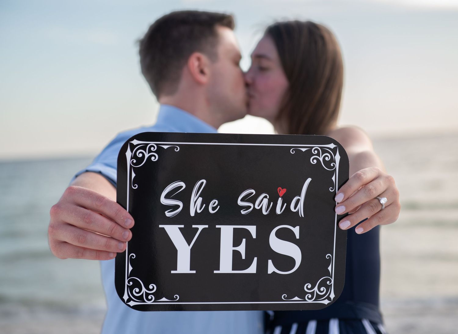 Series of chalkboard signs spelling out a proposal message on the beach.