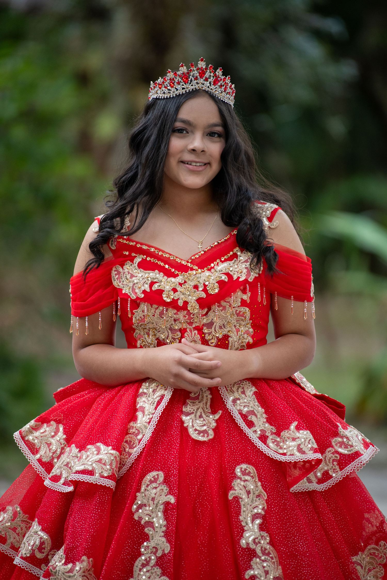 Beautiful red ball gown with gold embellishments and tiara for quinceañera portraits. Quinceañera photoshoot.