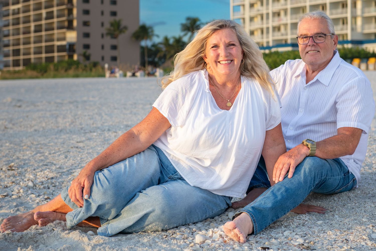 Couple lounging on white sandy beach near beachfront condos.