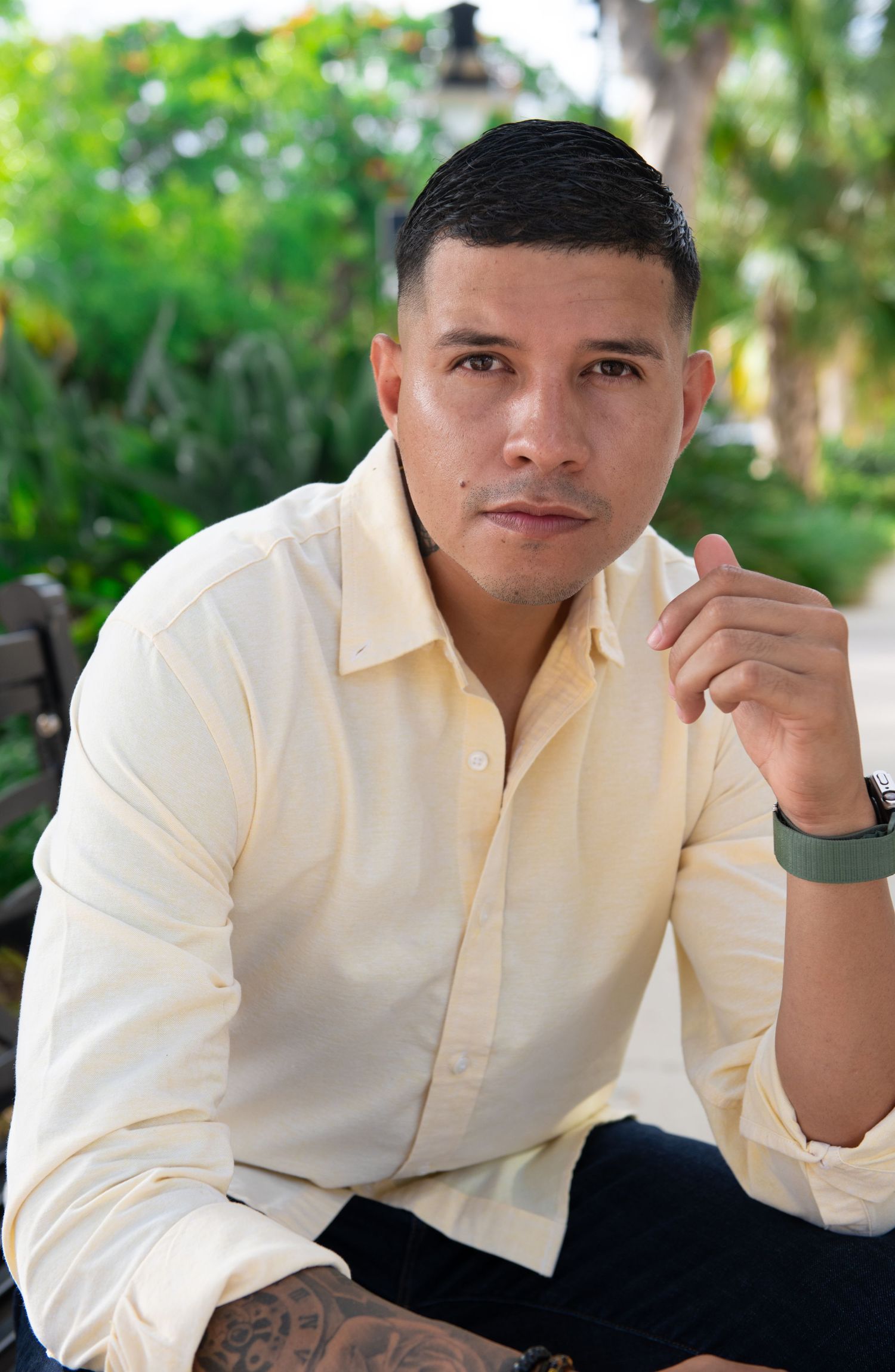 Stylish casual portrait against lush tropical garden backdrop with cream colored button-down shirt.