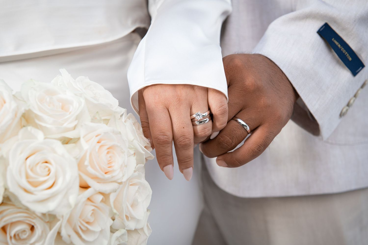 Wedding detail shots showing white roses and engagement rings.