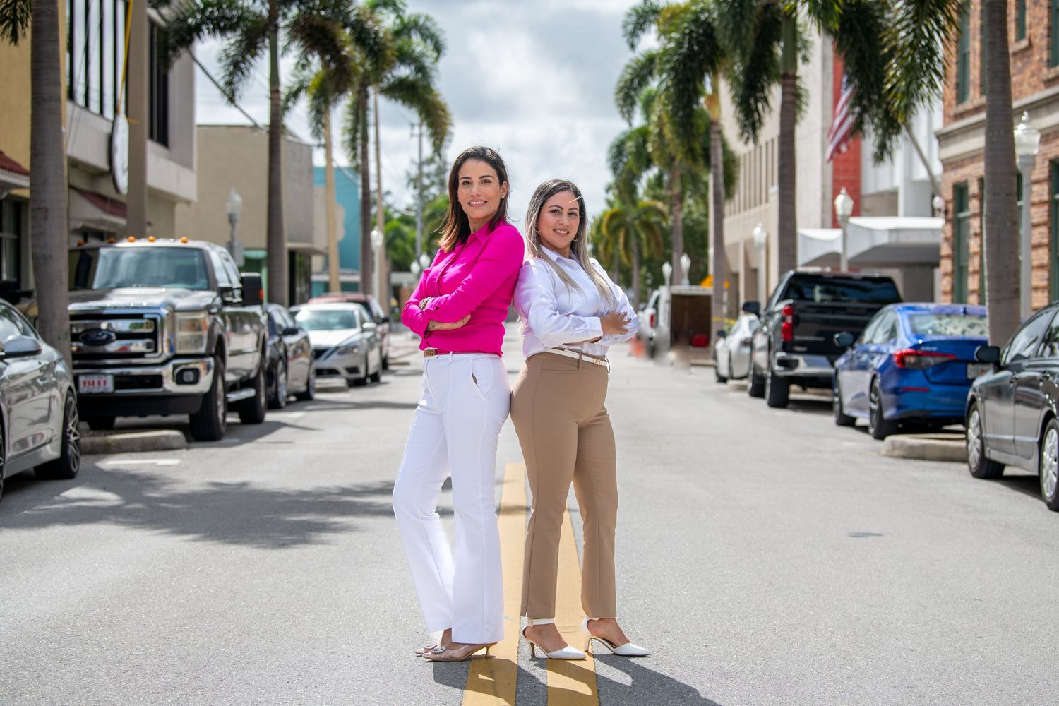 Two colleagues walking down a palm tree-lined street in business attire.