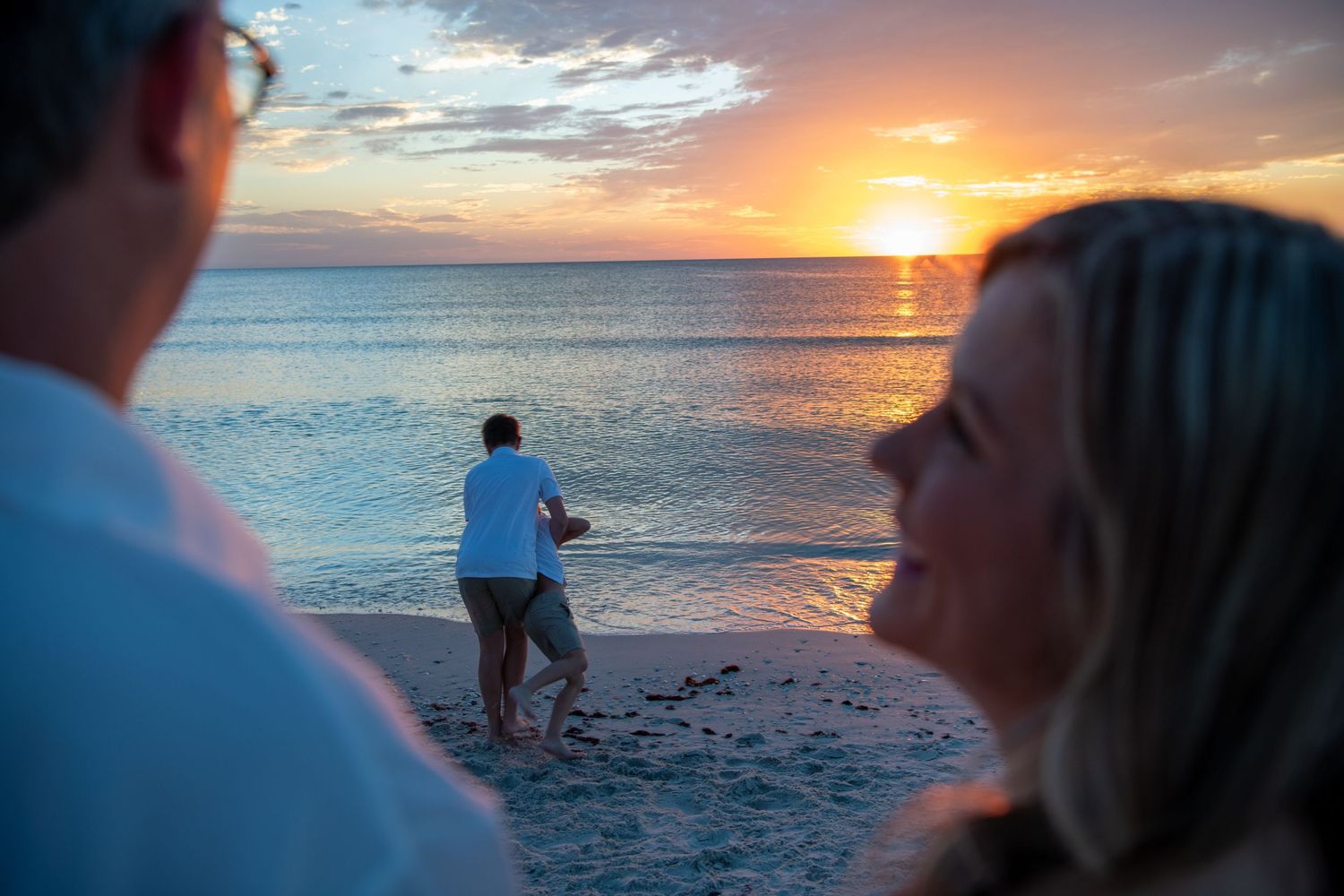 Silhouettes watching a photographer working on beach during golden sunset. Beach photoshoot. Family photoshoot,