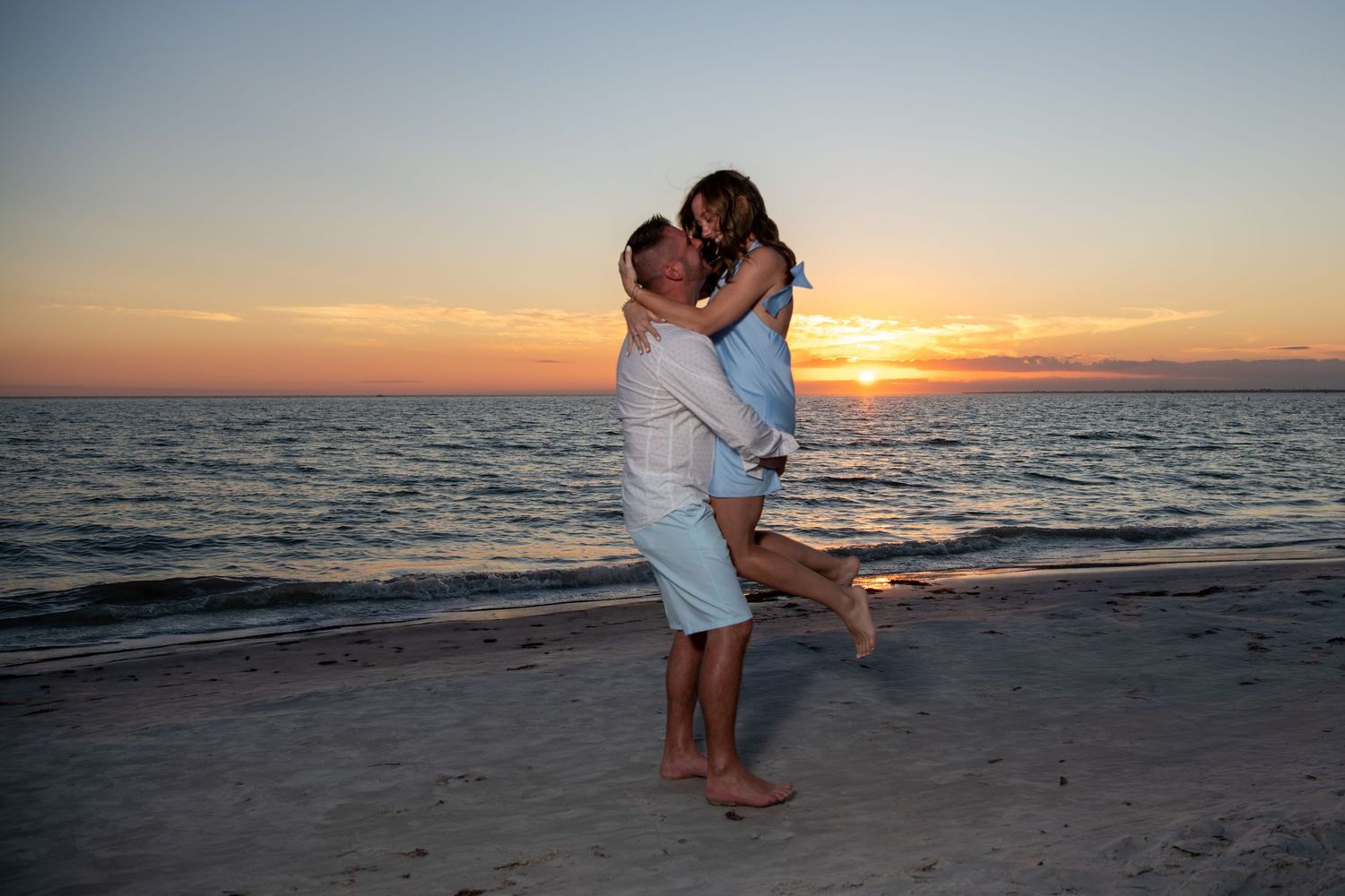 Intimate moment captured between couple on sandy beach at dusk. Engagement photoshoot. Couples photos.