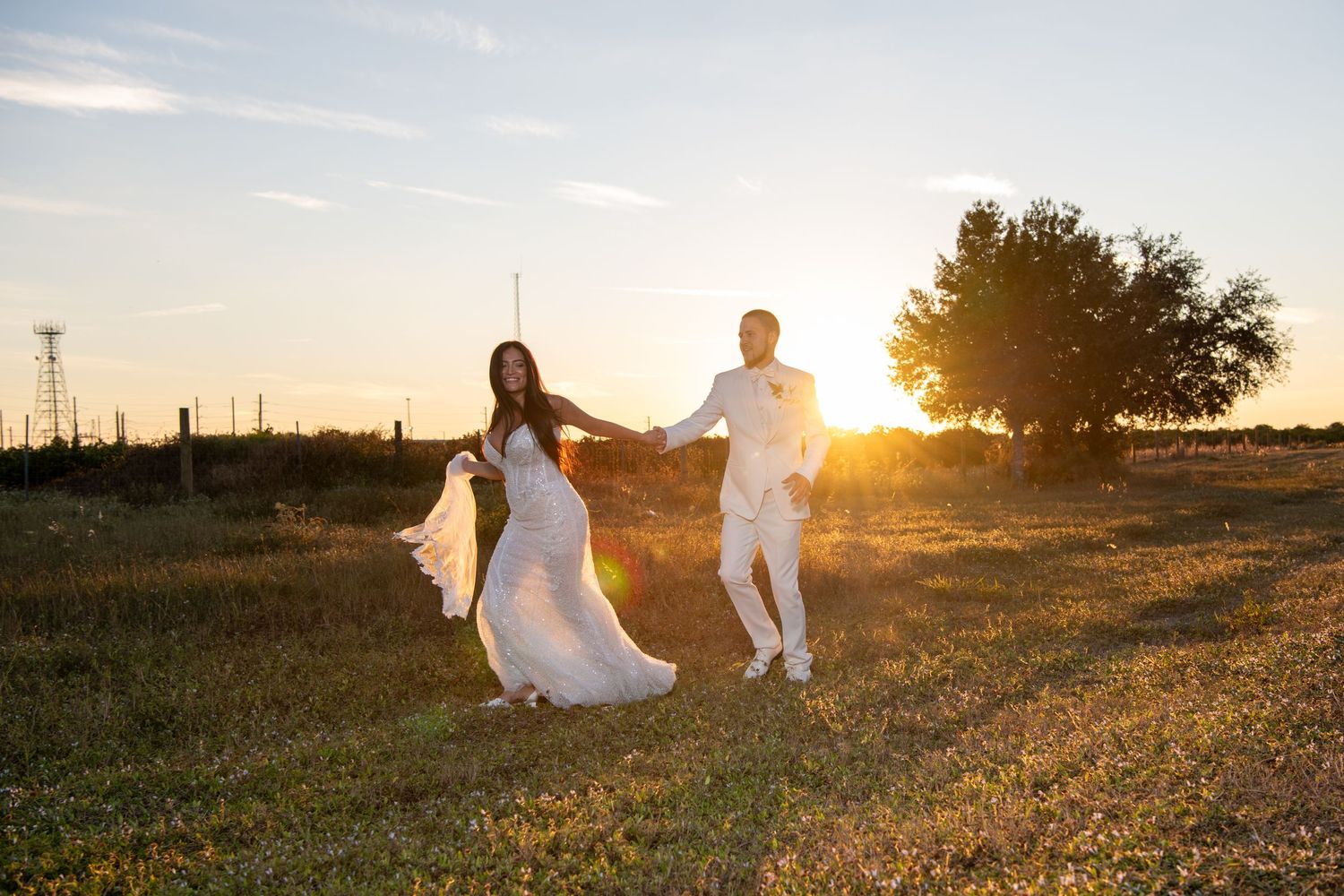 Wedding couple runs playfully through field during golden hour photo session. Wedding photography.